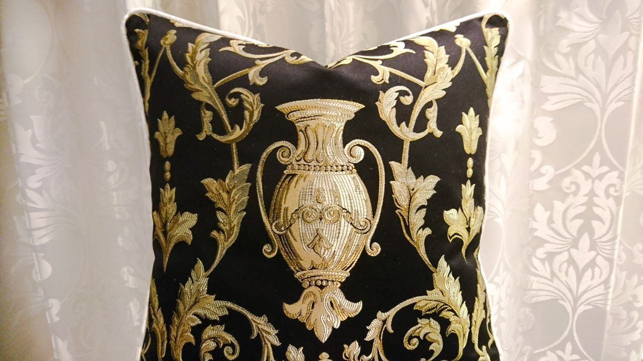Ein schwarz-goldenes Kissen mit einer Vase darauf