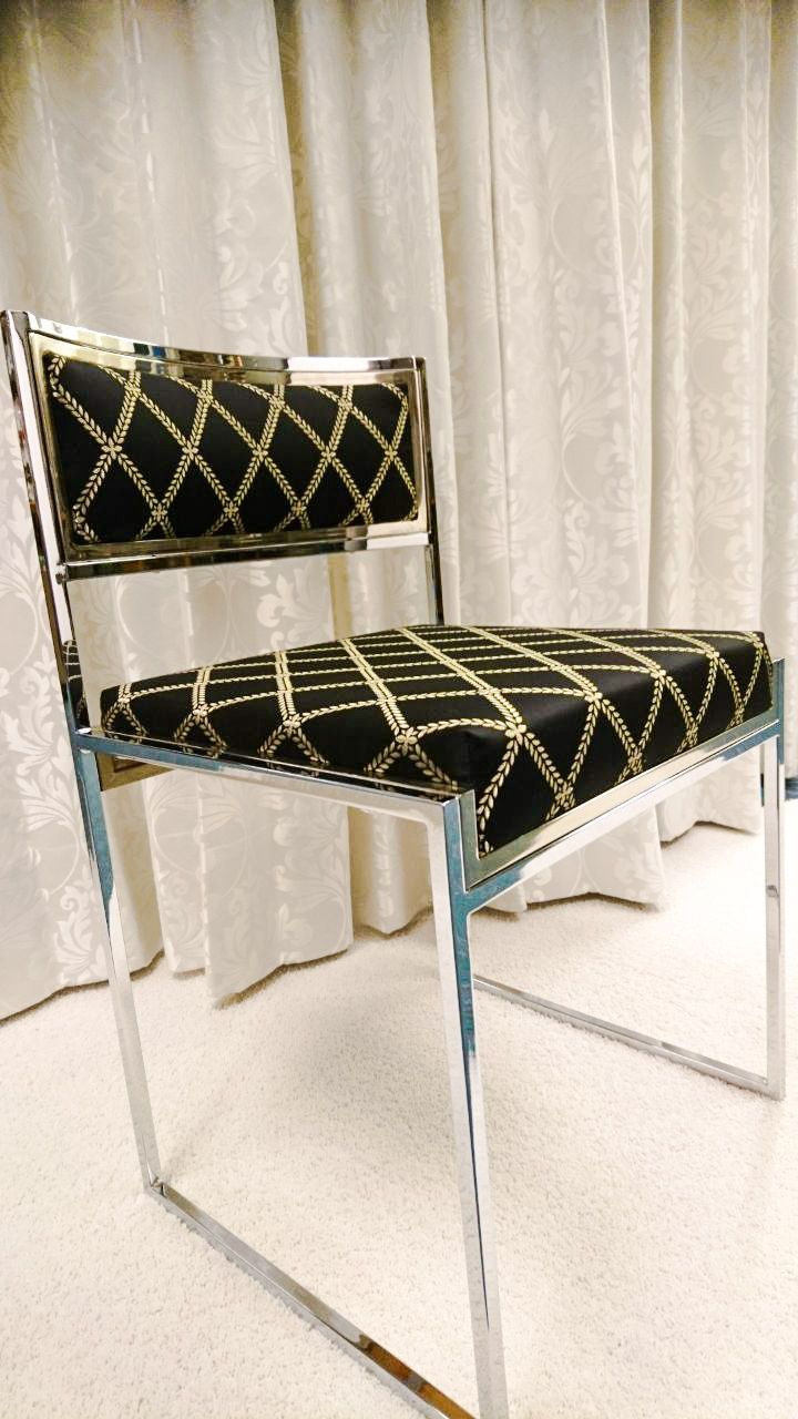 Vor einem weißen Vorhang steht ein schwarz-goldener Stuhl.