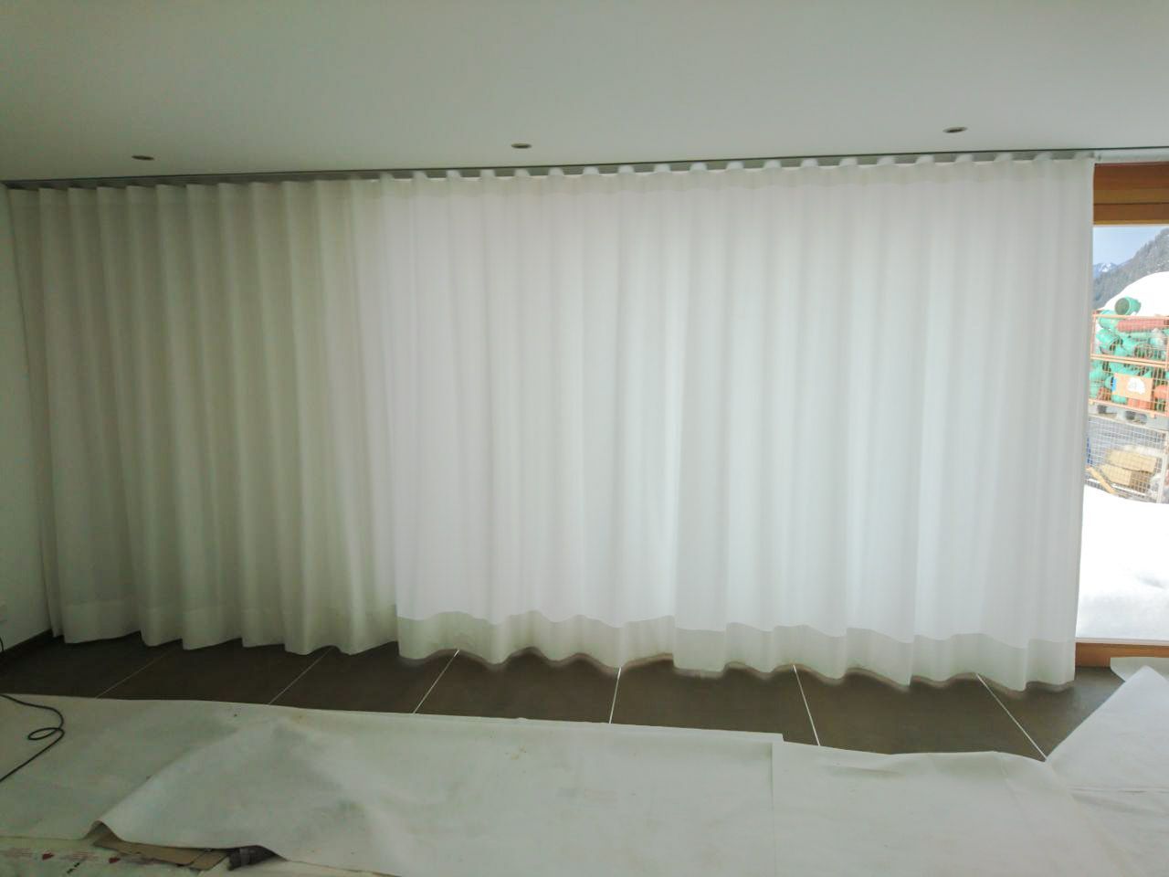 Ein Zimmer mit weißen Vorhängen und einem großen Fenster