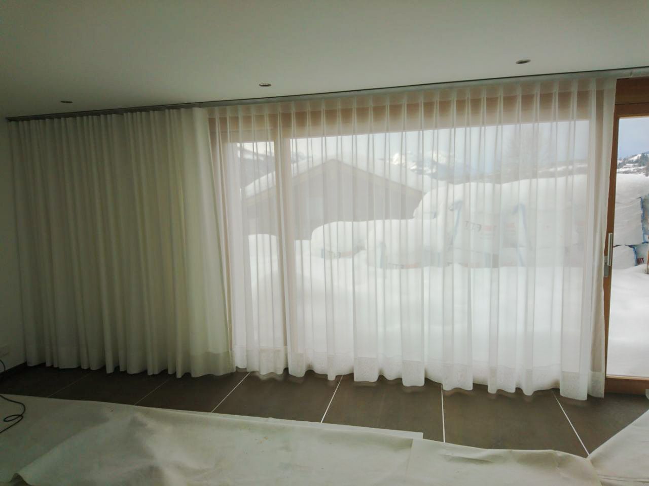 Ein Zimmer mit einer Glasschiebetür und weißen Vorhängen