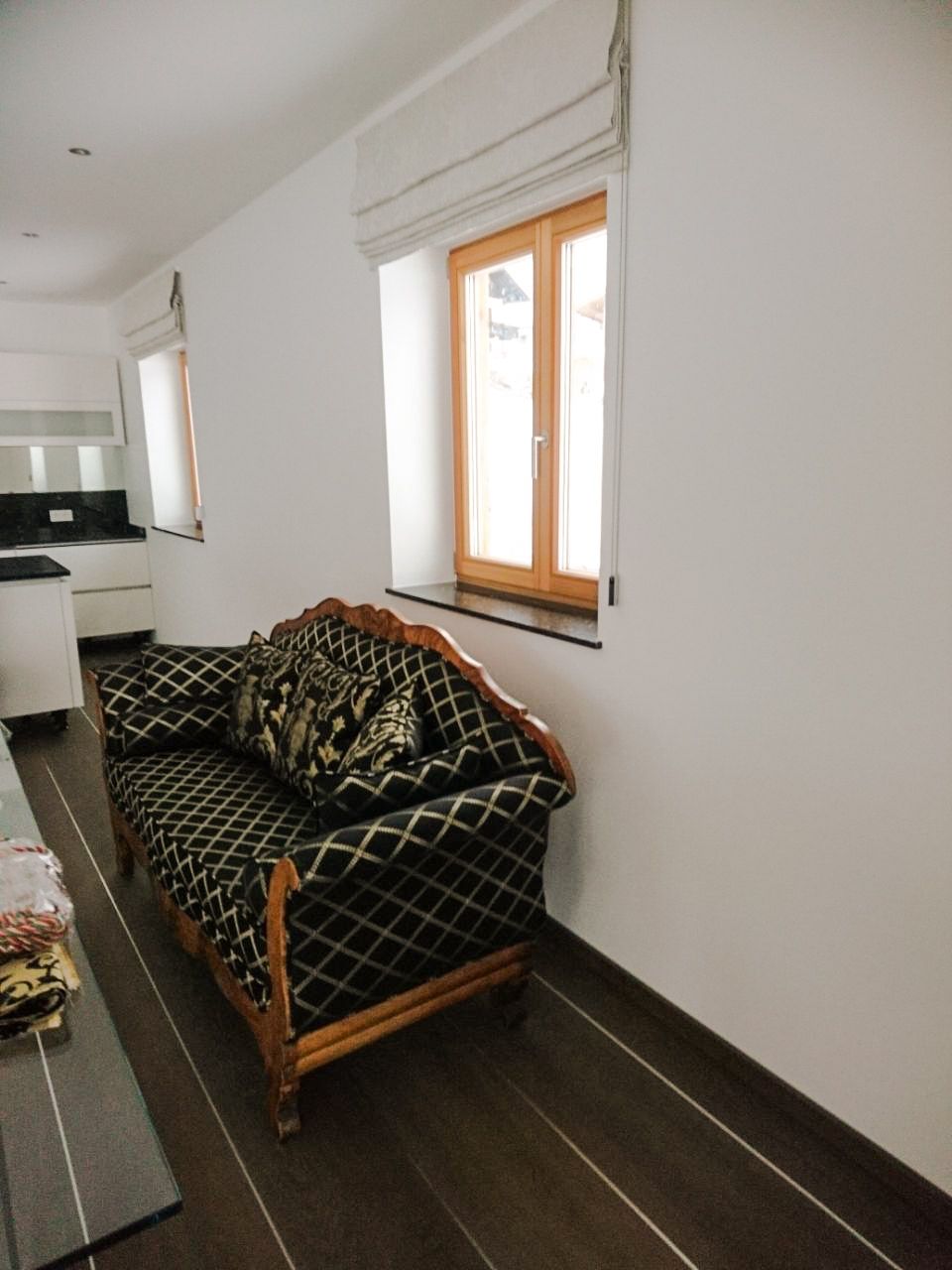 Ein Wohnzimmer mit einer Couch und zwei Fenstern