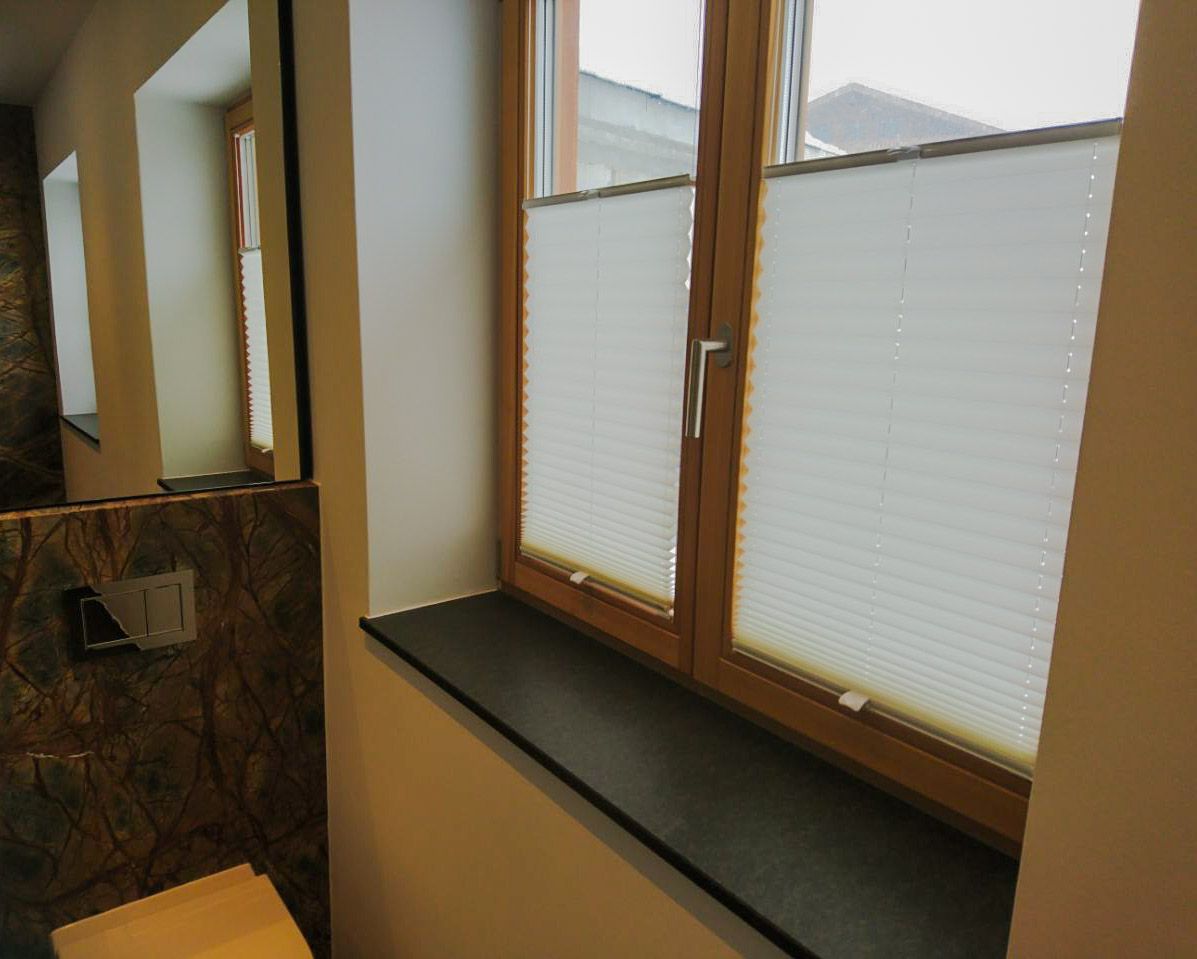 Ein Badezimmer mit Toilette und ein Fenster mit Jalousien