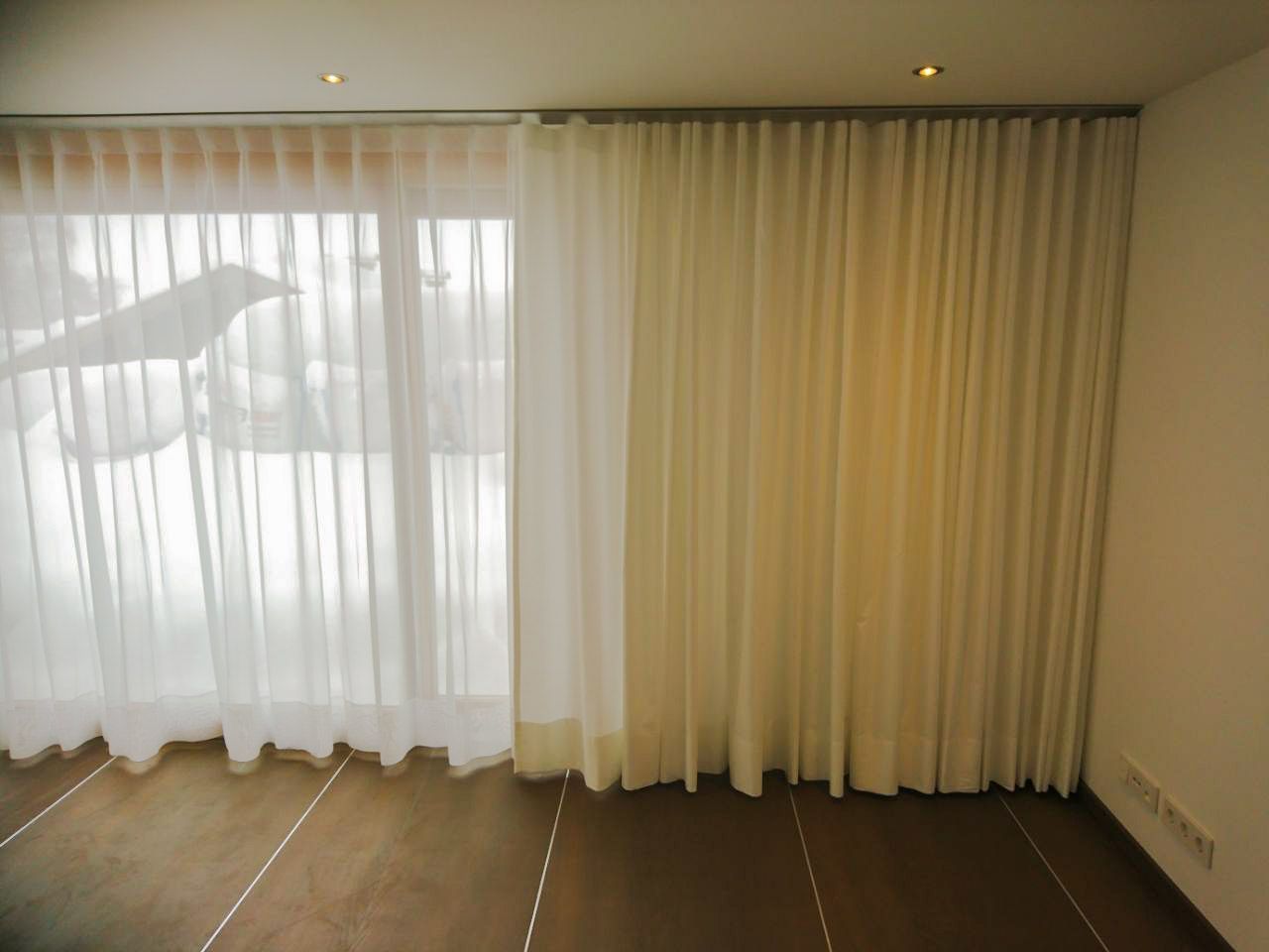Ein Zimmer mit einer Glasschiebetür und weißen Vorhängen