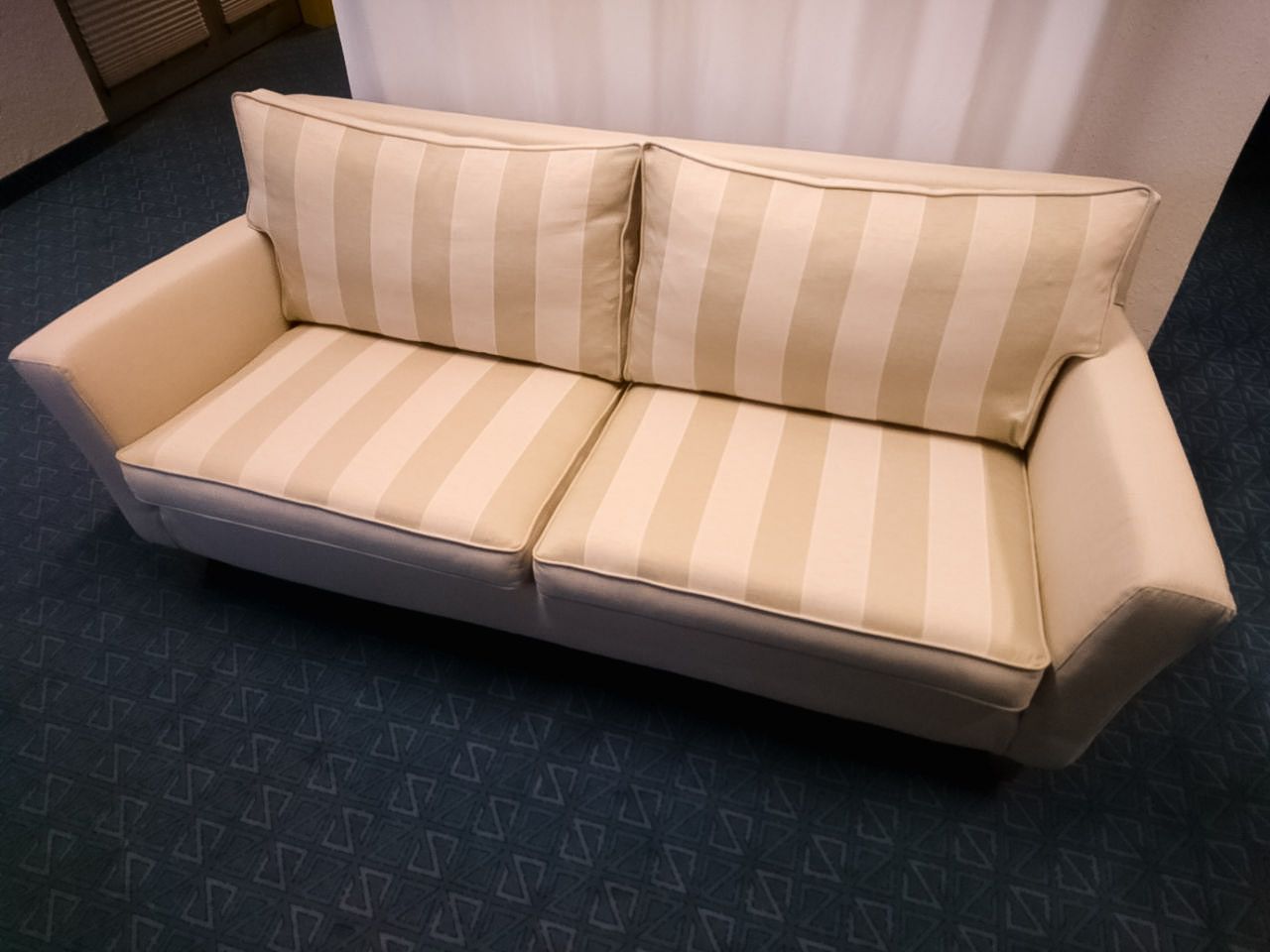 Eine weiß gestreifte Couch steht auf einem blauen Teppich