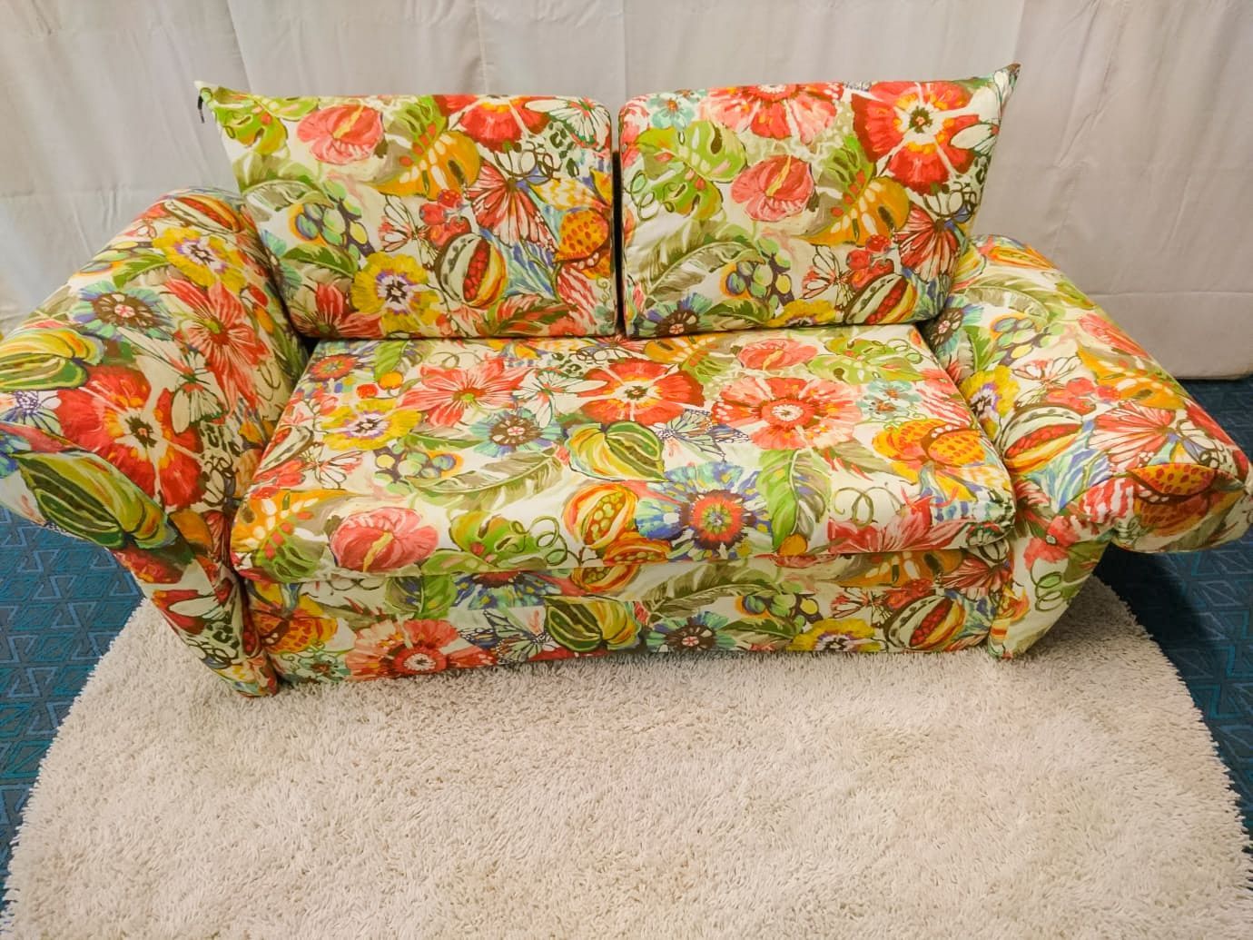 Eine farbenfrohe Blumencouch steht auf einem weißen Teppich