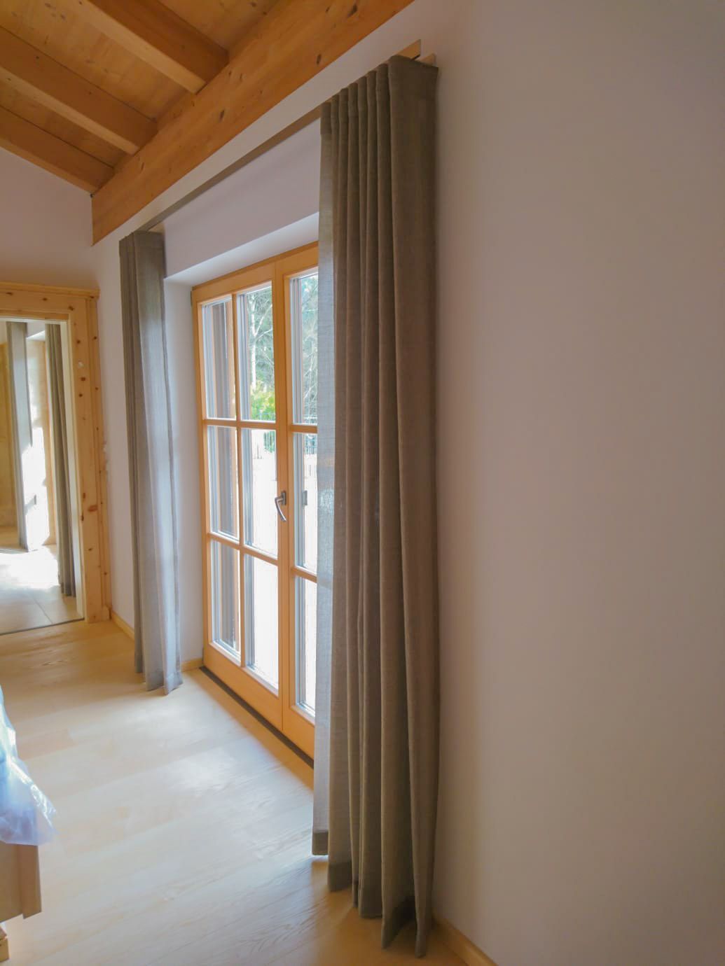 Ein Schlafzimmer mit großem Fenster und Vorhängen.