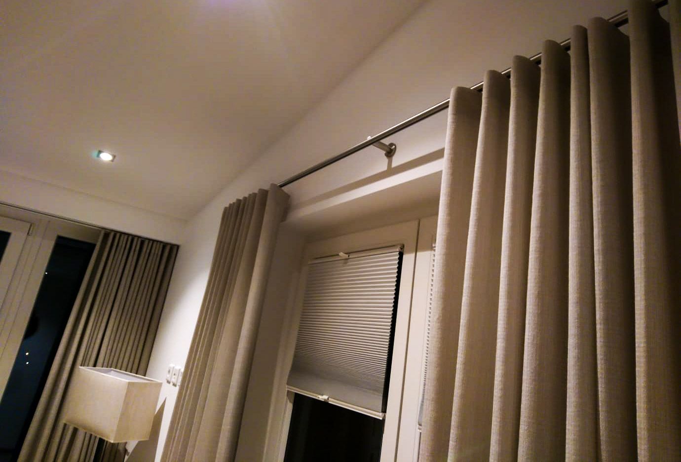 Ein Zimmer mit einem Fenster, Vorhängen und einer Lampe.