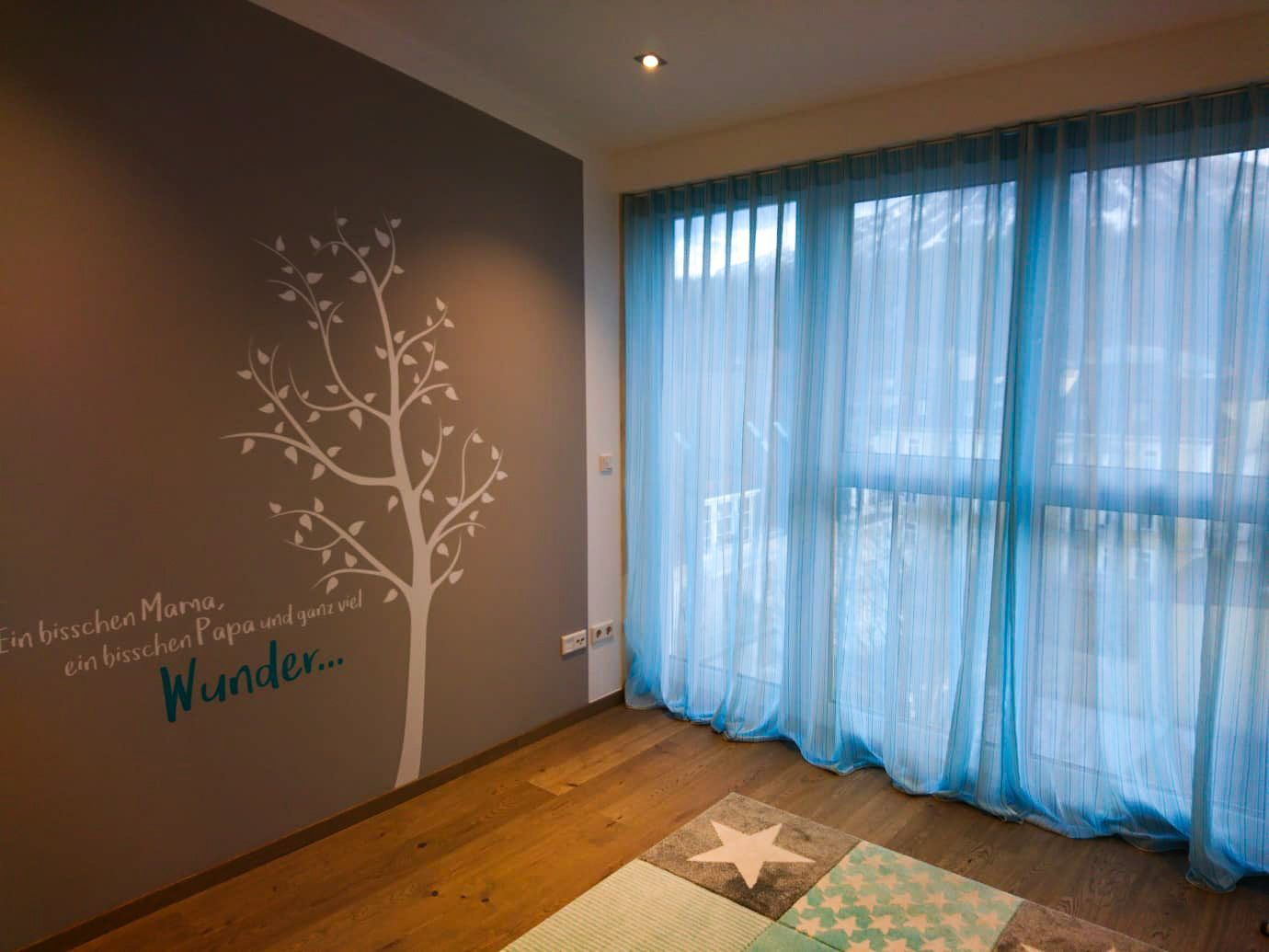 Ein Zimmer mit einem Baum an der Wand und blauen Vorhängen