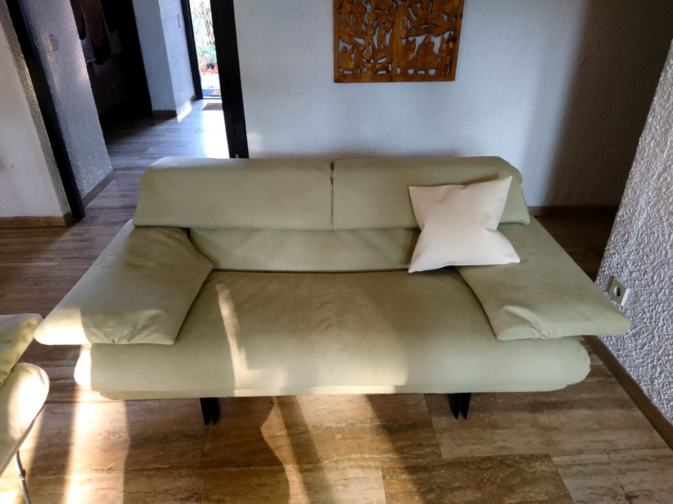 Eine Couch mit einem weißen Kissen darauf in einem Wohnzimmer
