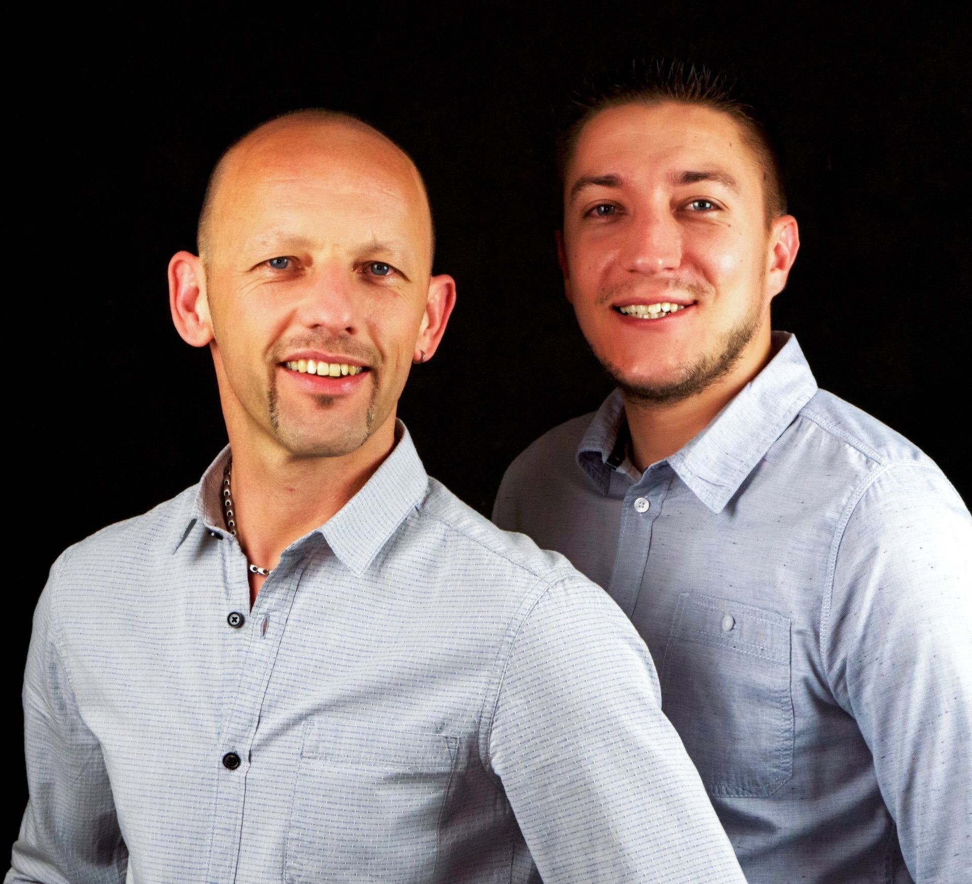 Zwei Männer stehen nebeneinander und lächeln in die Kamera.