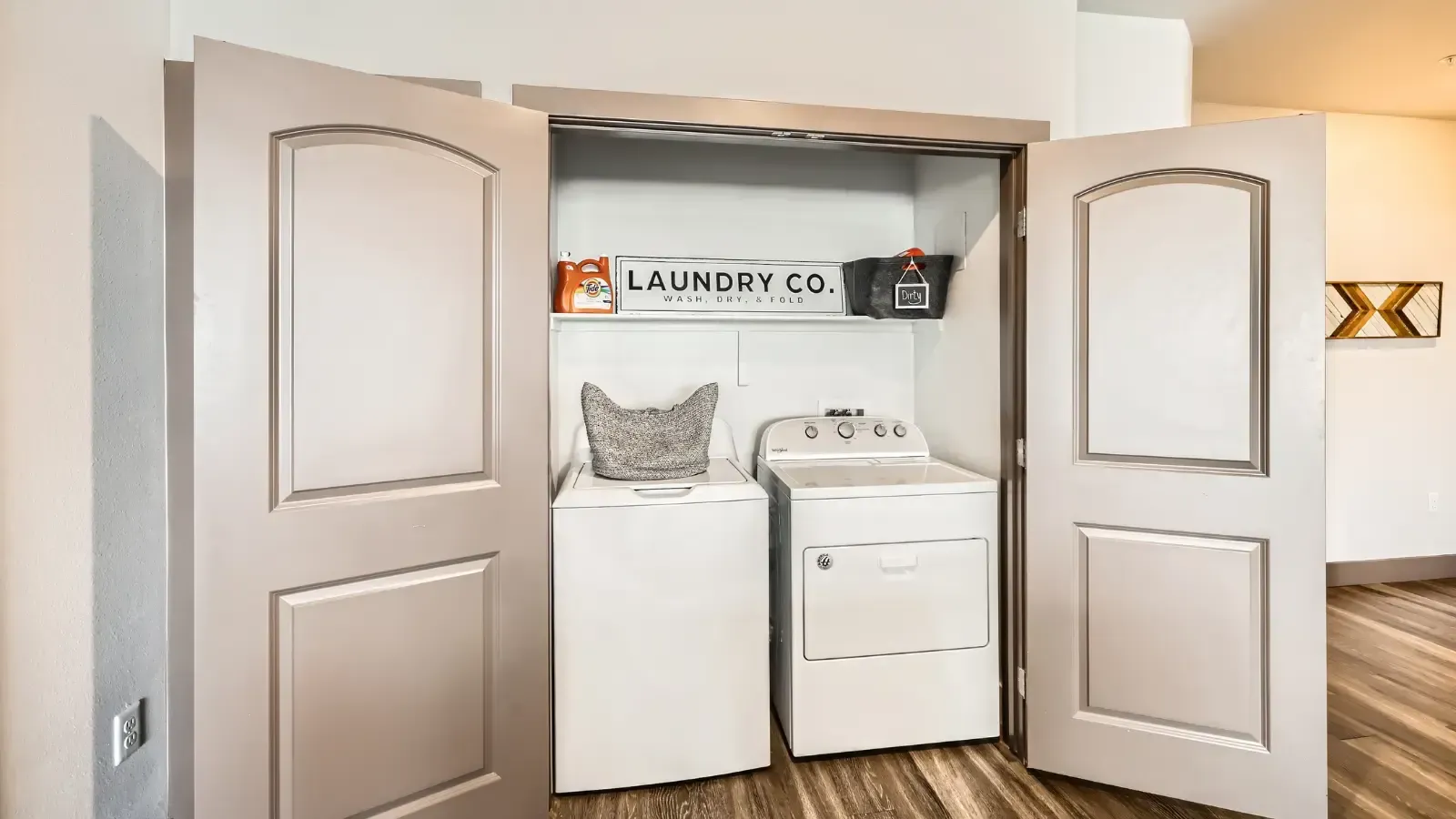 Laundry closet with a top-load washer and a front-load dryer behind open double doors.