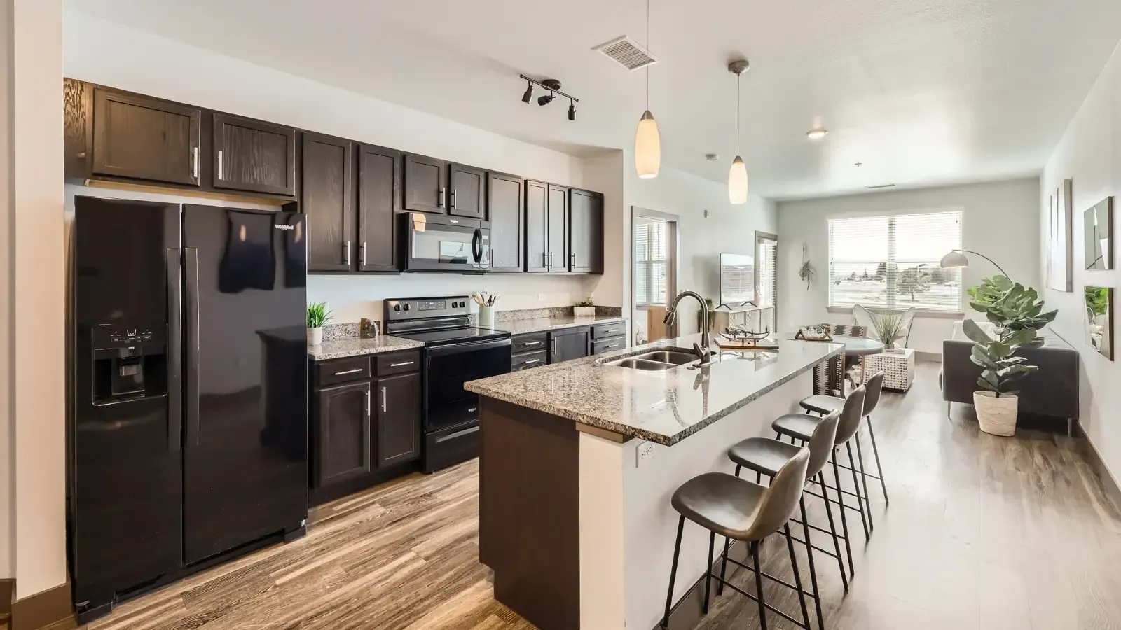 Open-concept kitchen with dark cabinets, granite countertops, and a breakfast island.