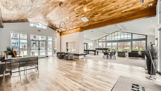 Spacious lobby with wood ceiling and floors, seating areas, and a view of an outdoor pool.