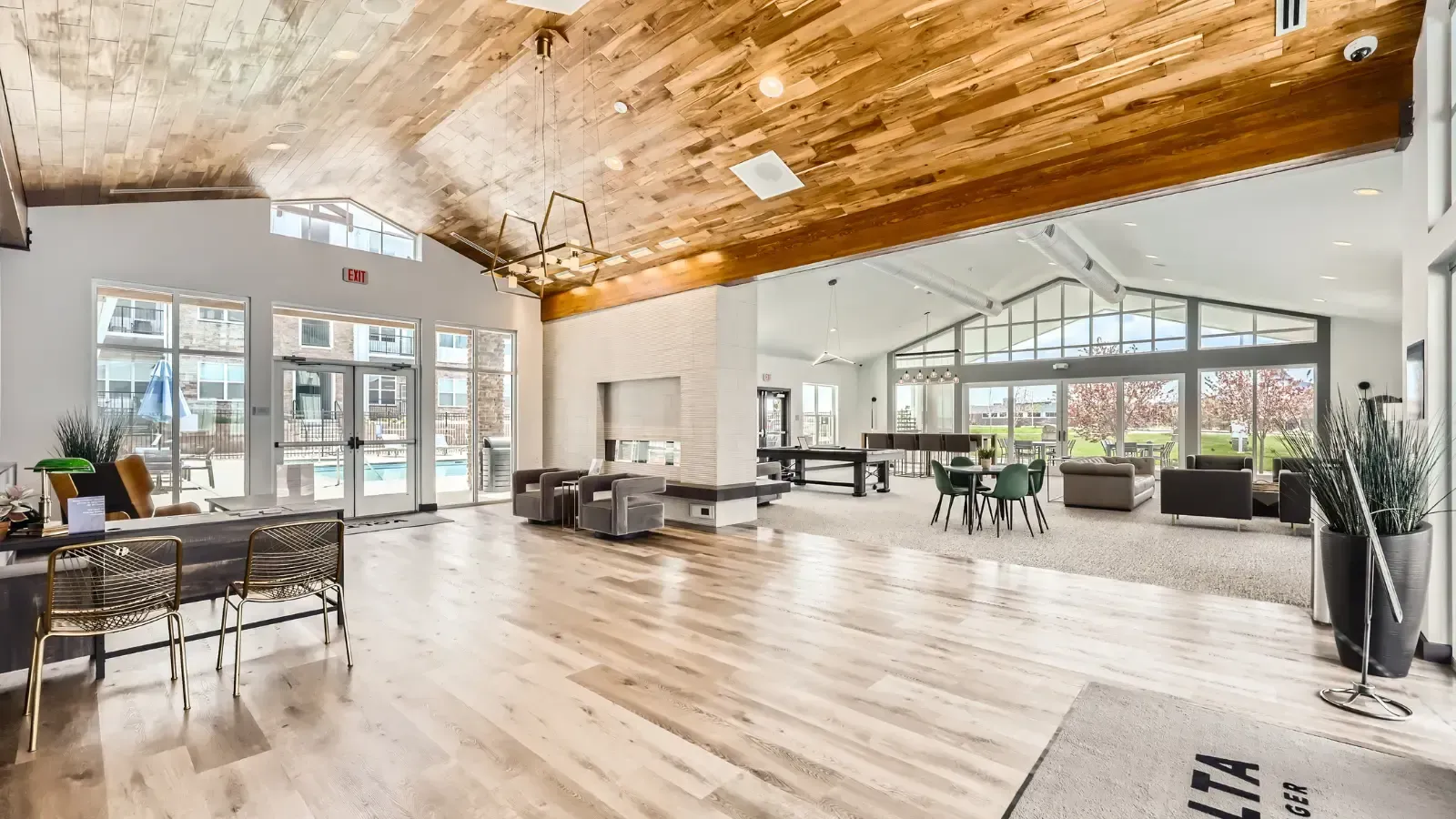 Spacious community lounge with a wood-plank ceiling, modern seating, and large glass walls.
