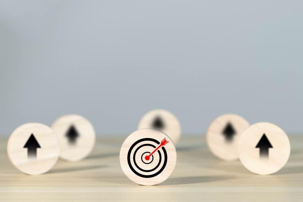 Wooden target with a bullseye and an arrow, surrounded by wooden blocks with upward-pointing arrows.