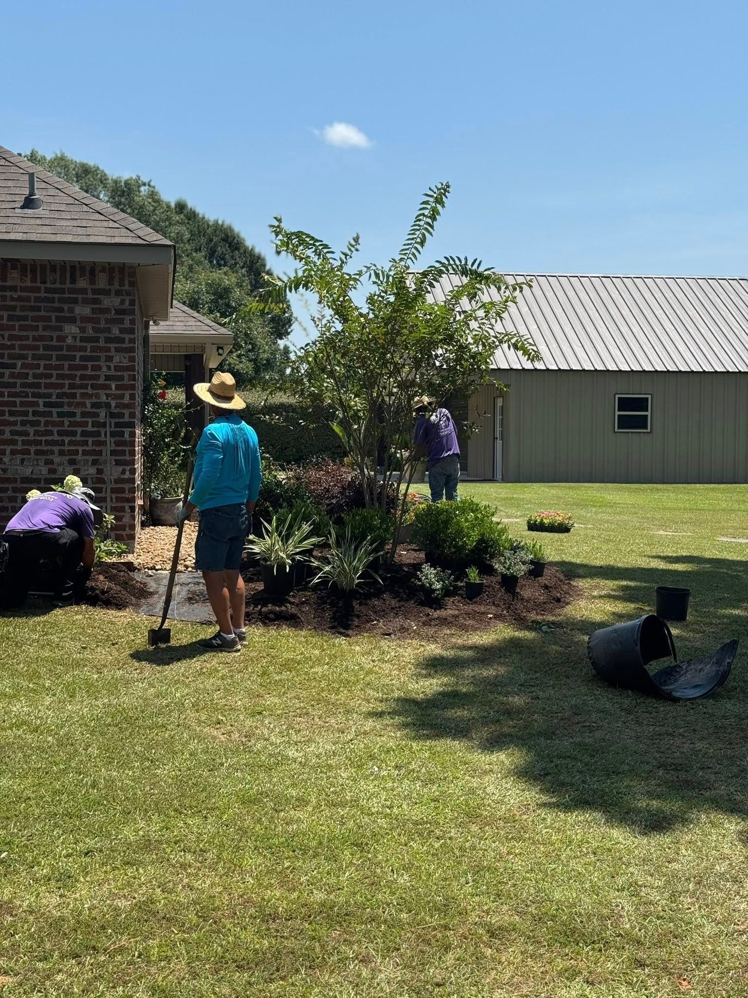 People gardening a flower bed in a sunny backyard.