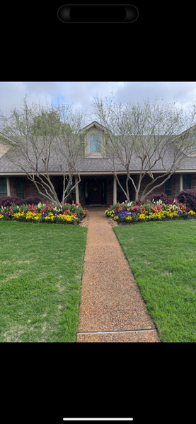 A house with a stone path leading to the front door. Landscaping includes colorful flowers and trees.