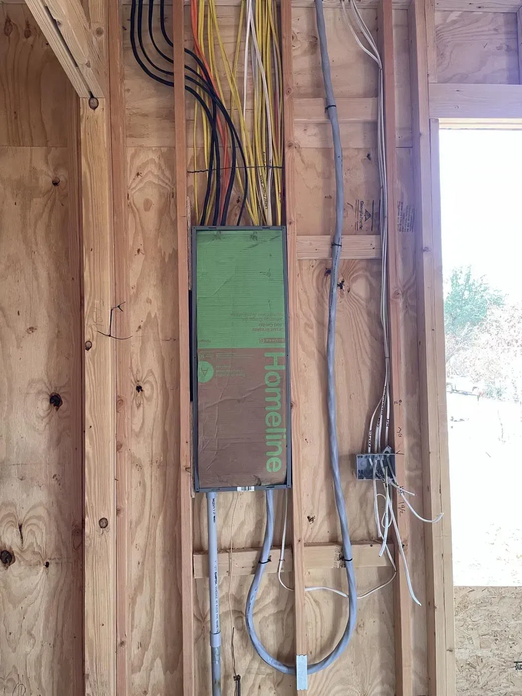Electrical panel box with wiring installed in a wooden wall.