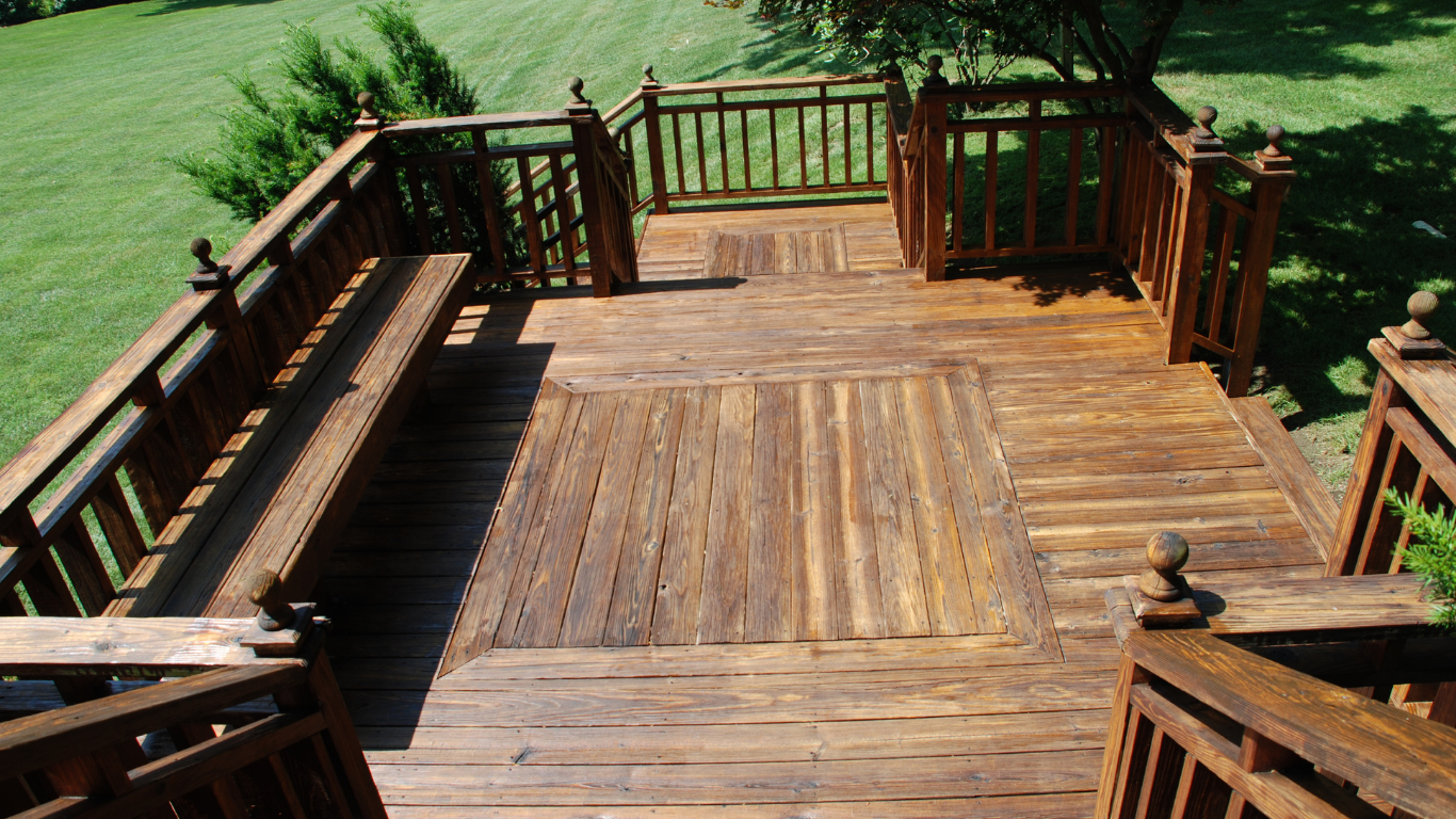 A high-angle view of a wooden deck featuring a built-in bench, surrounding railings, and a central inlay design.