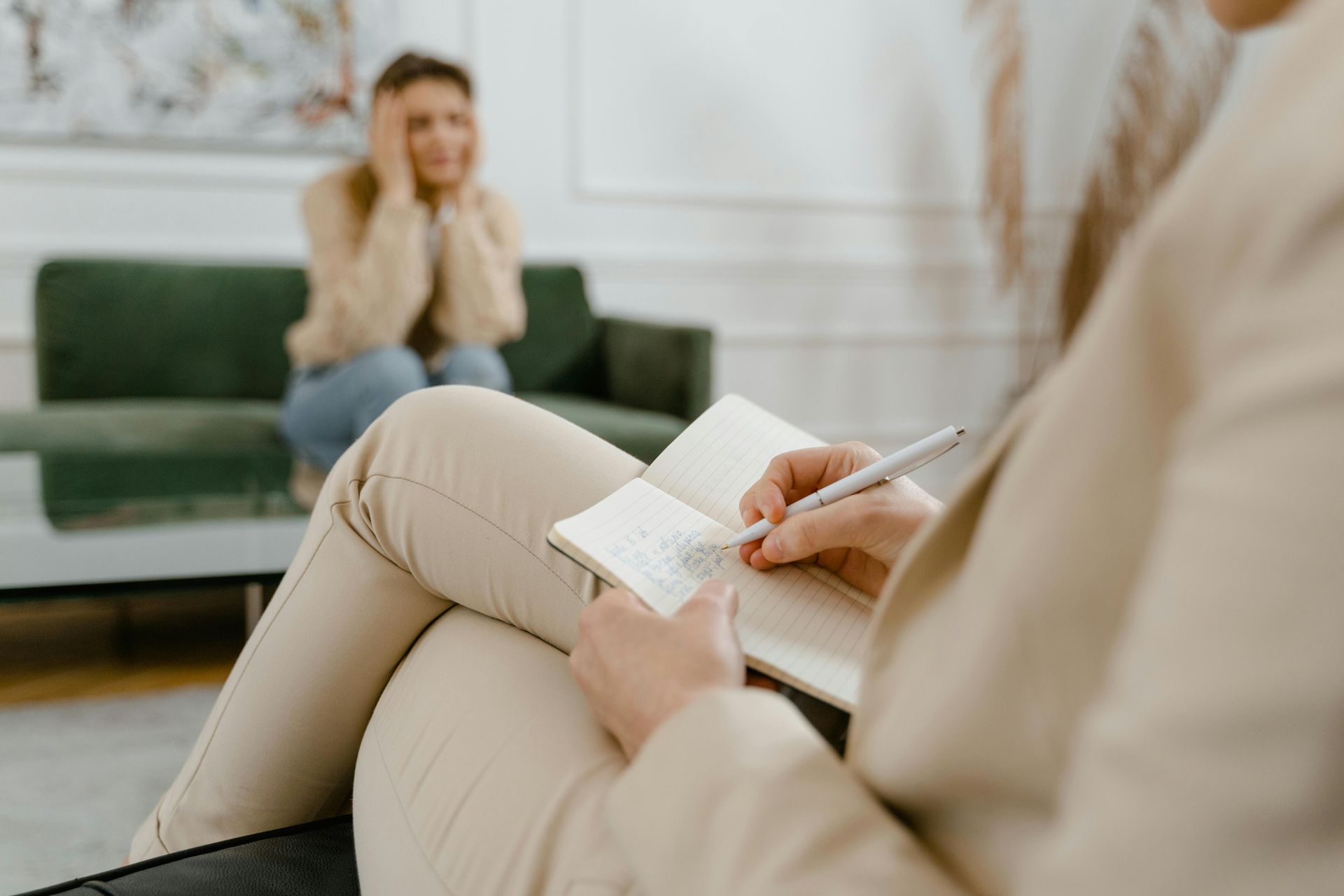 A woman is sitting on a couch talking to a female psychologist.