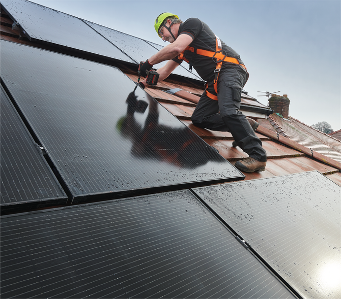 A man is installing solar panels on a roof