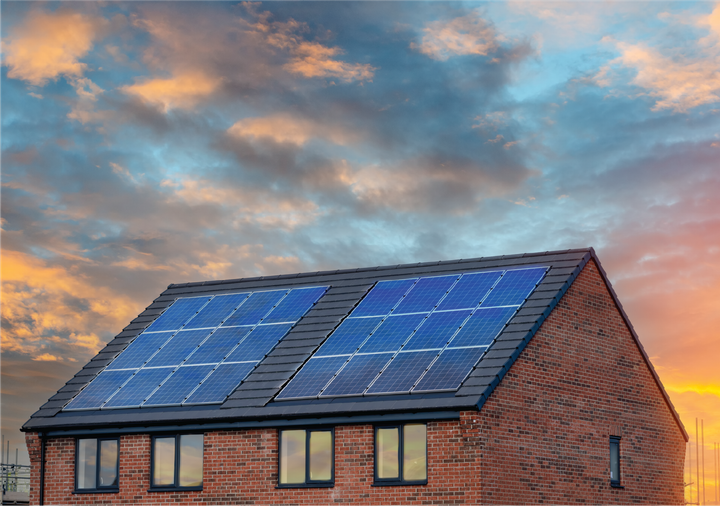 A brick house with solar panels on the roof at sunset.