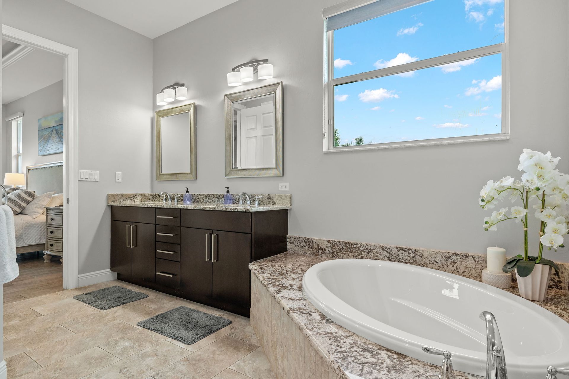 A bathroom with two sinks, a tub, and a window.