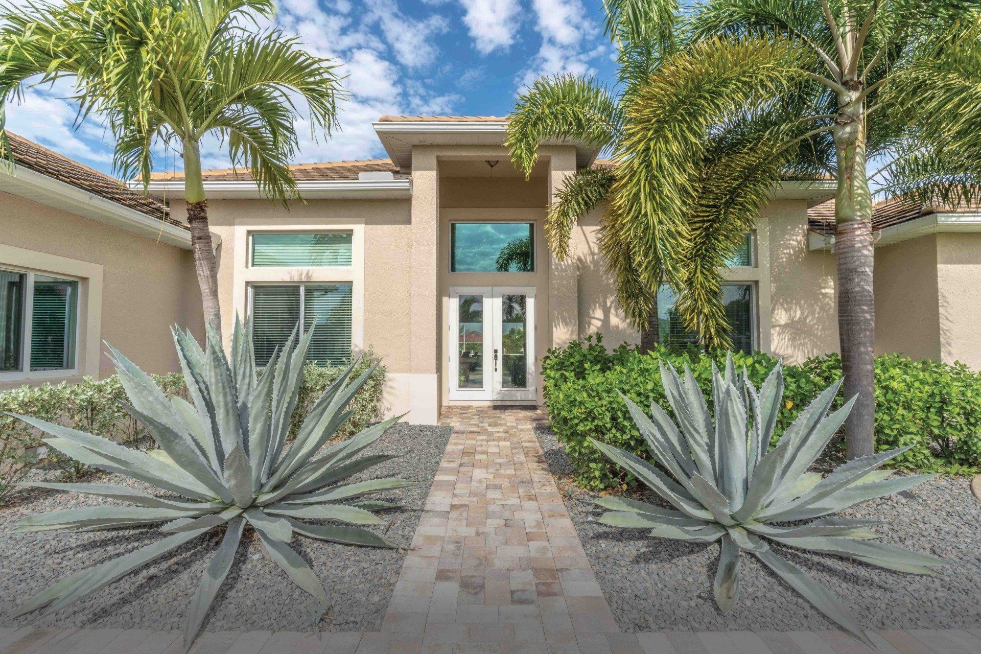 A walkway leads to the front door surrounded by palm trees of Congo Breeze, a vacation rental in Cape Coral, FL.