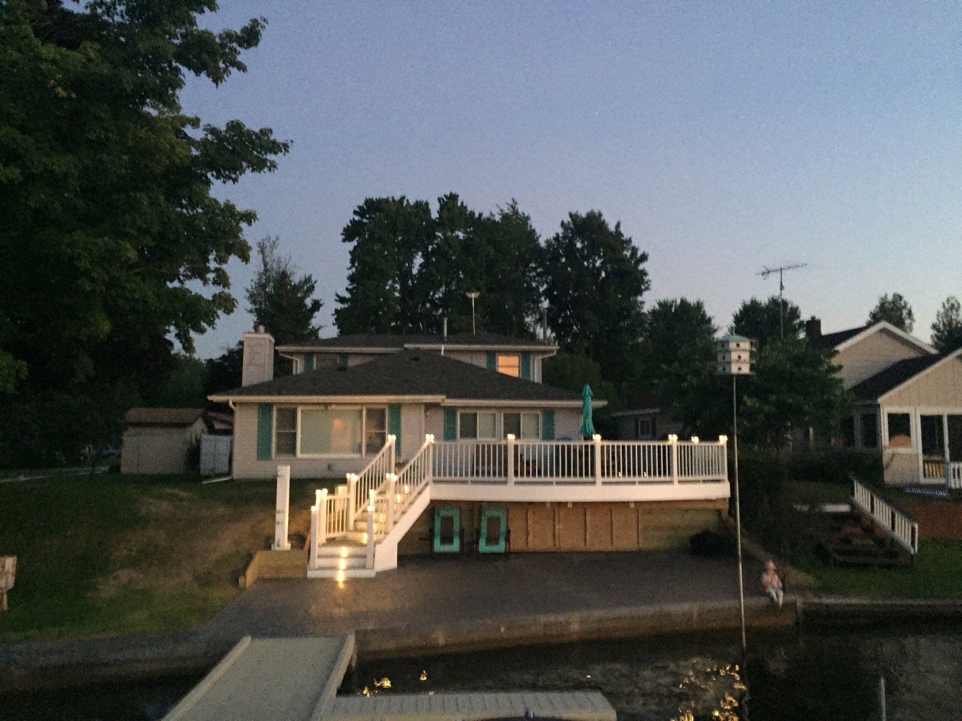 A house with a large deck sits next to a body of water