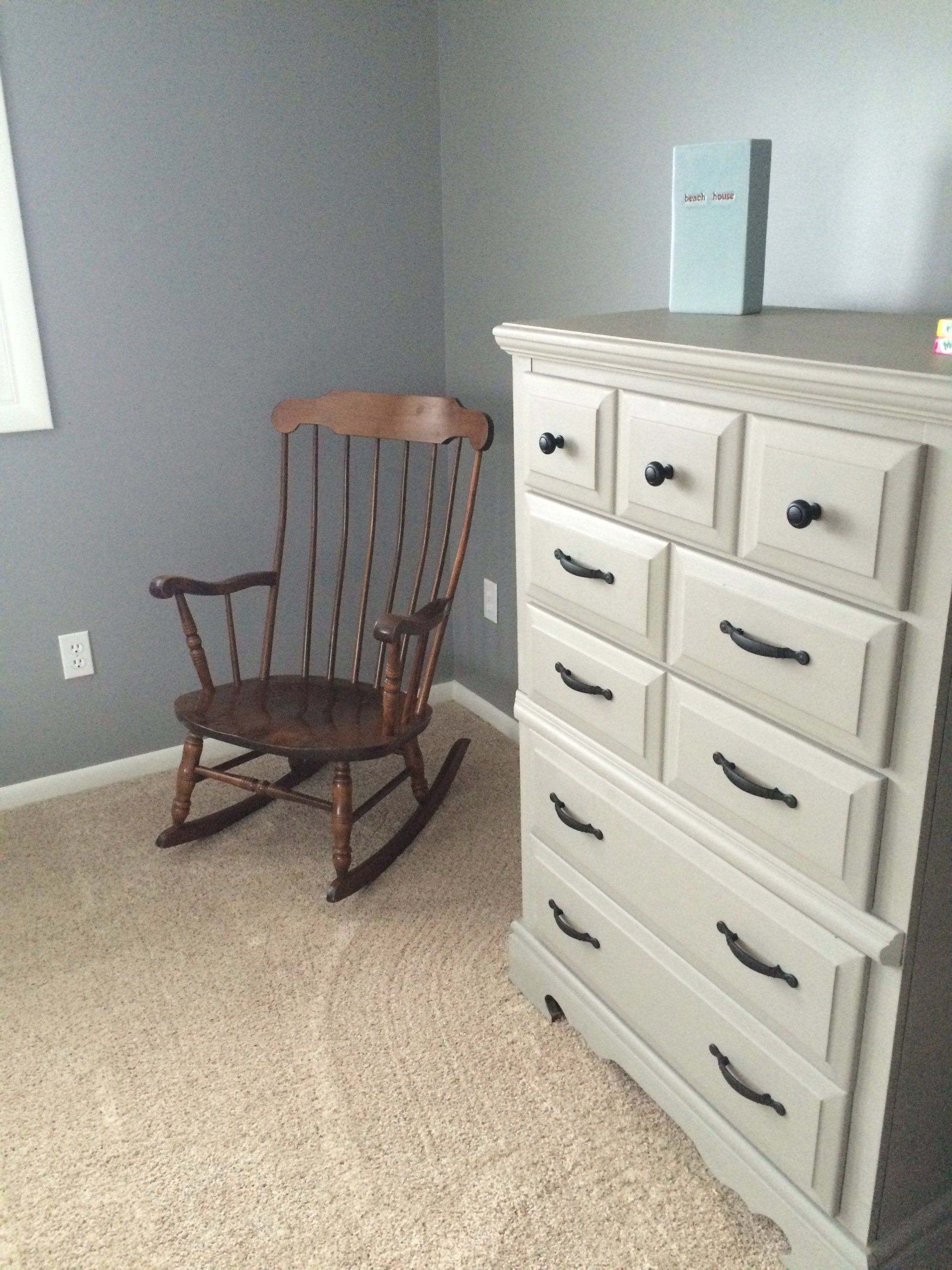 A rocking chair sits next to a dresser in a bedroom