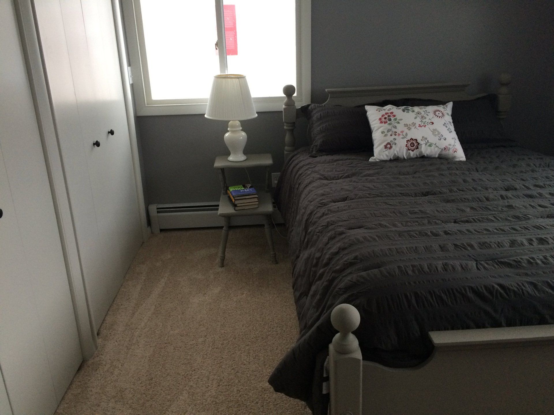 A bedroom with a bed a lamp and a window