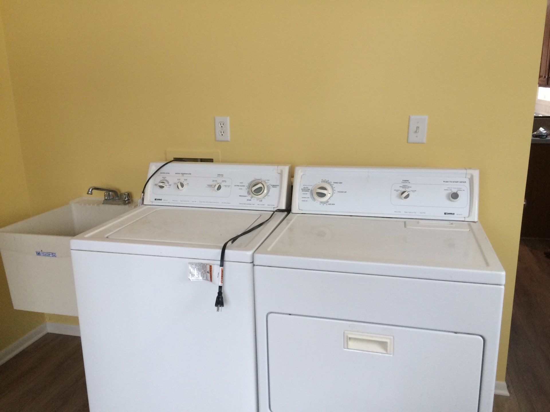 A washer and dryer are in a laundry room next to a sink.