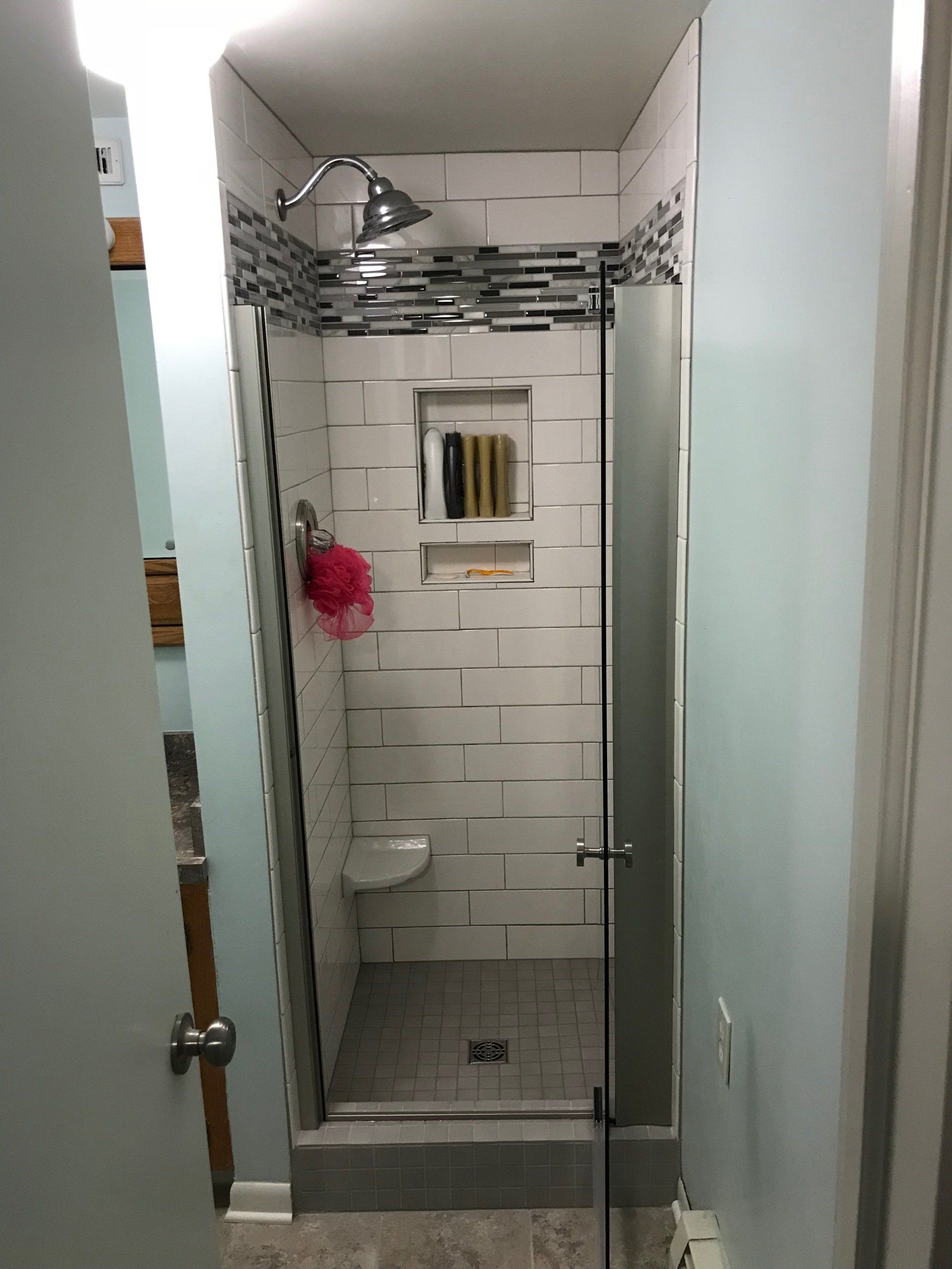 A bathroom with a walk in shower with a glass door.