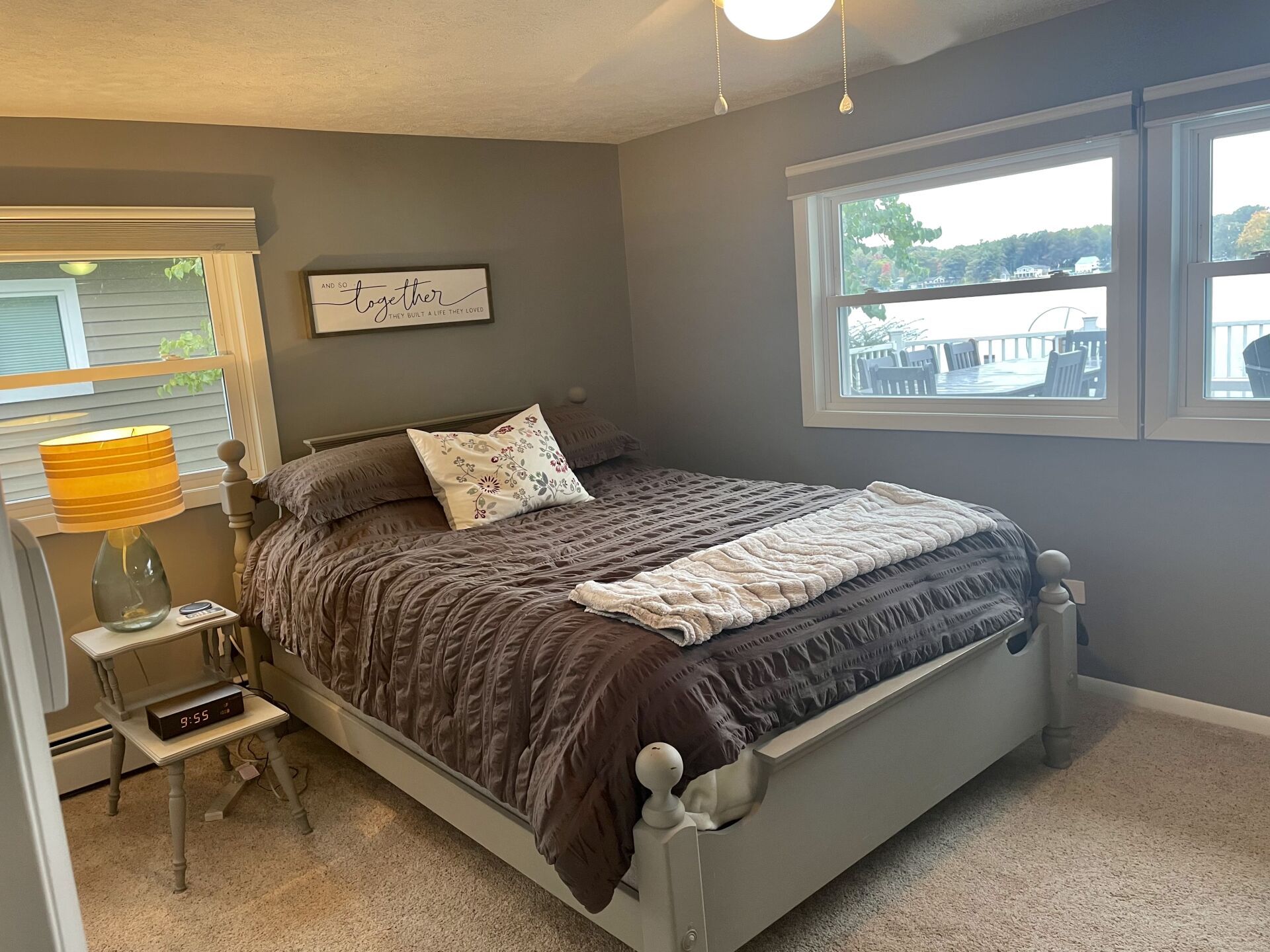 A bedroom with a bed, two windows, and a lamp.