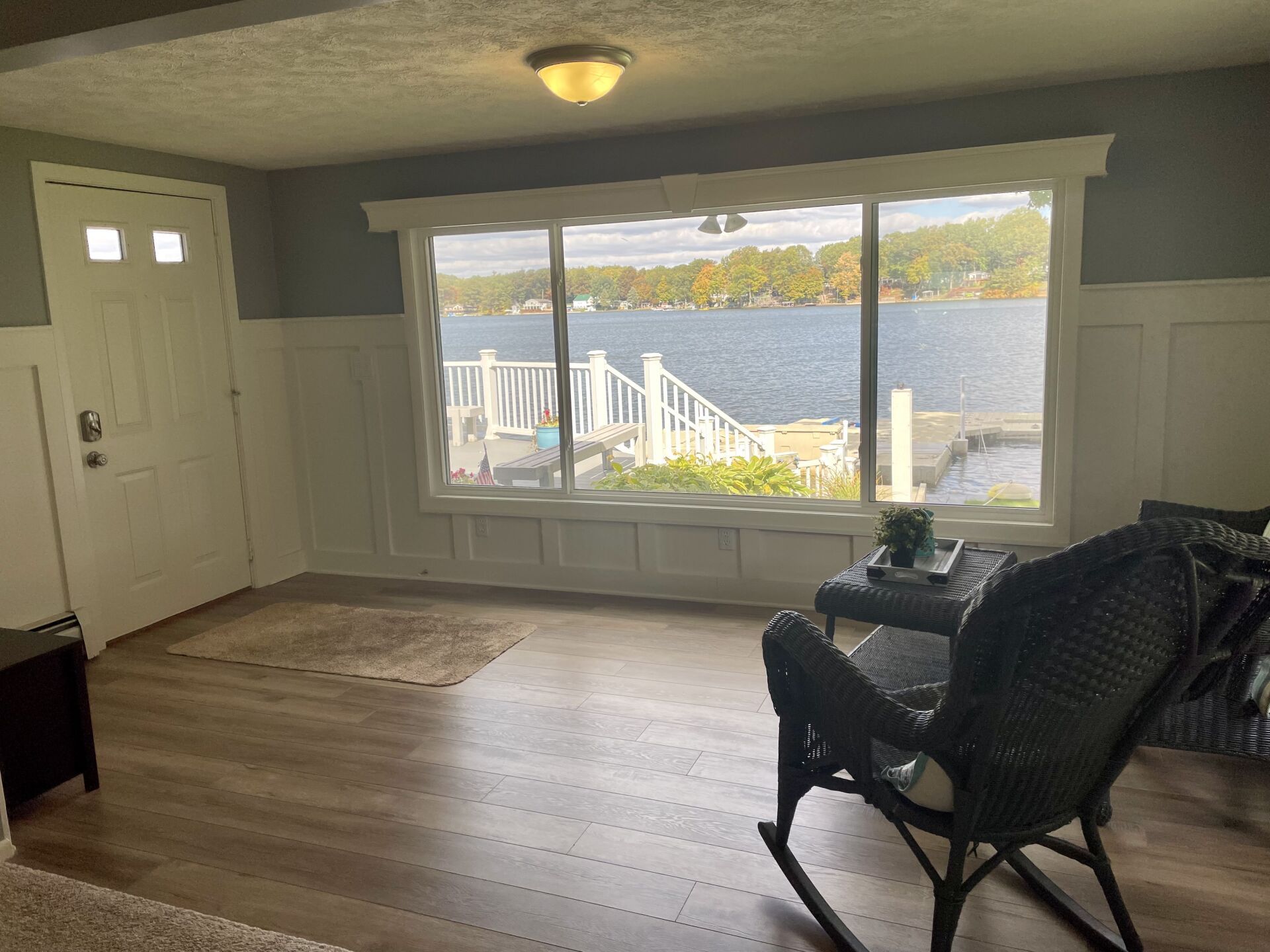 A living room with a rocking chair and a large window overlooking a lake.