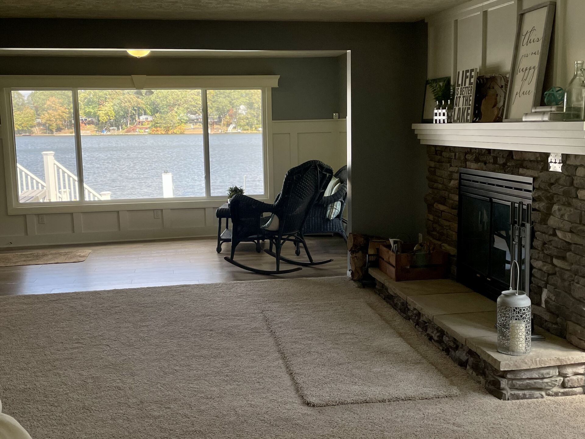 A living room with a rocking chair and a fireplace with a view of a lake.