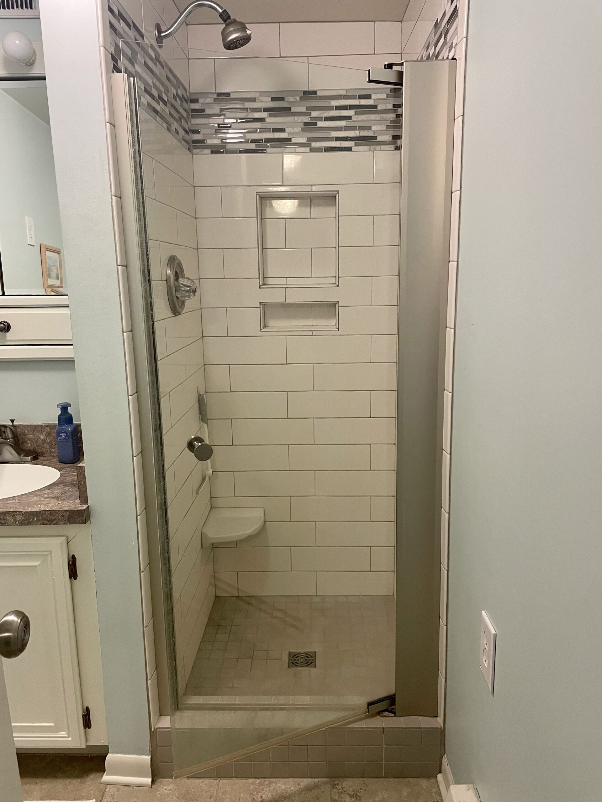 A bathroom with a walk in shower and a sink.