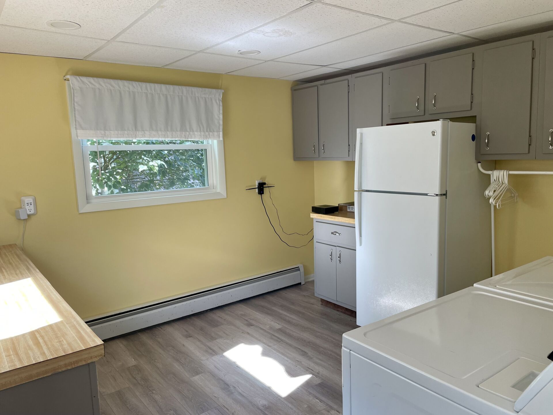 A kitchen with a refrigerator, washer and dryer, and a window.