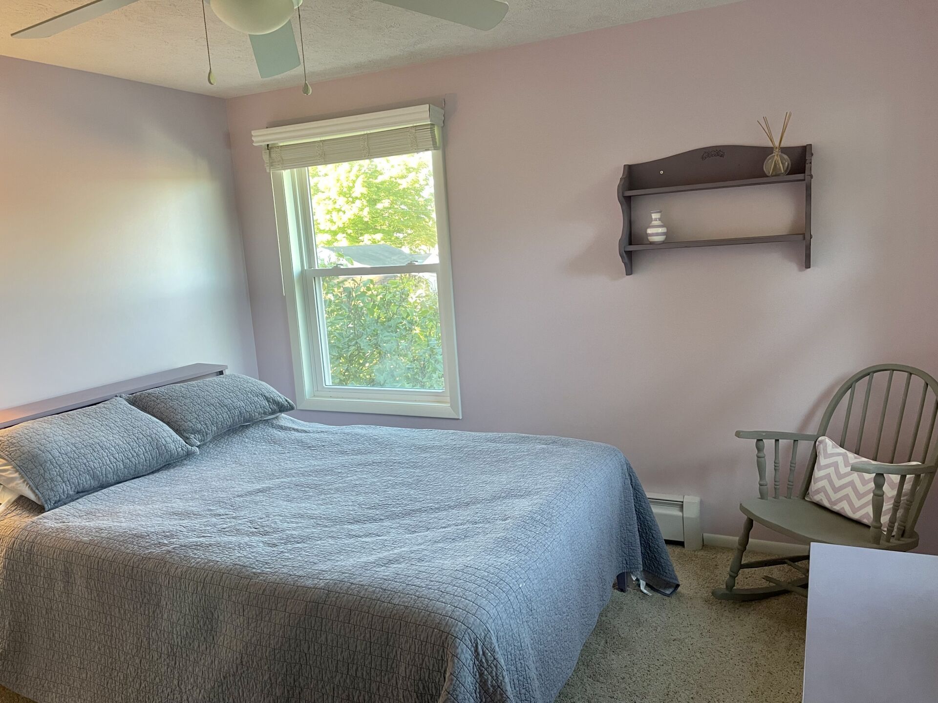 A bedroom with a bed and a rocking chair