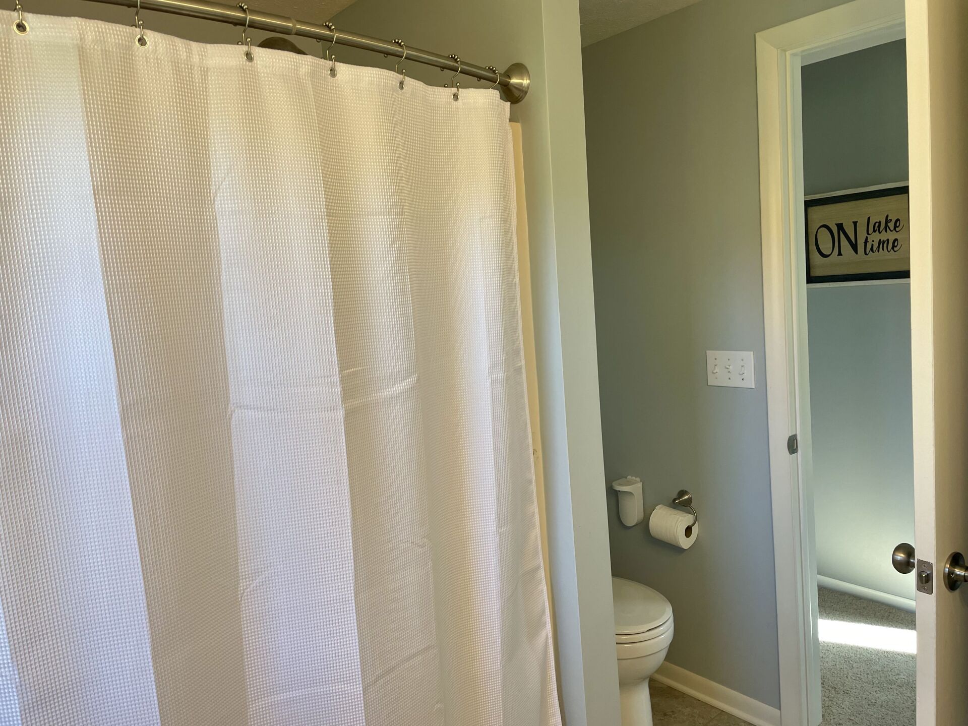 A bathroom with a shower curtain and a toilet.