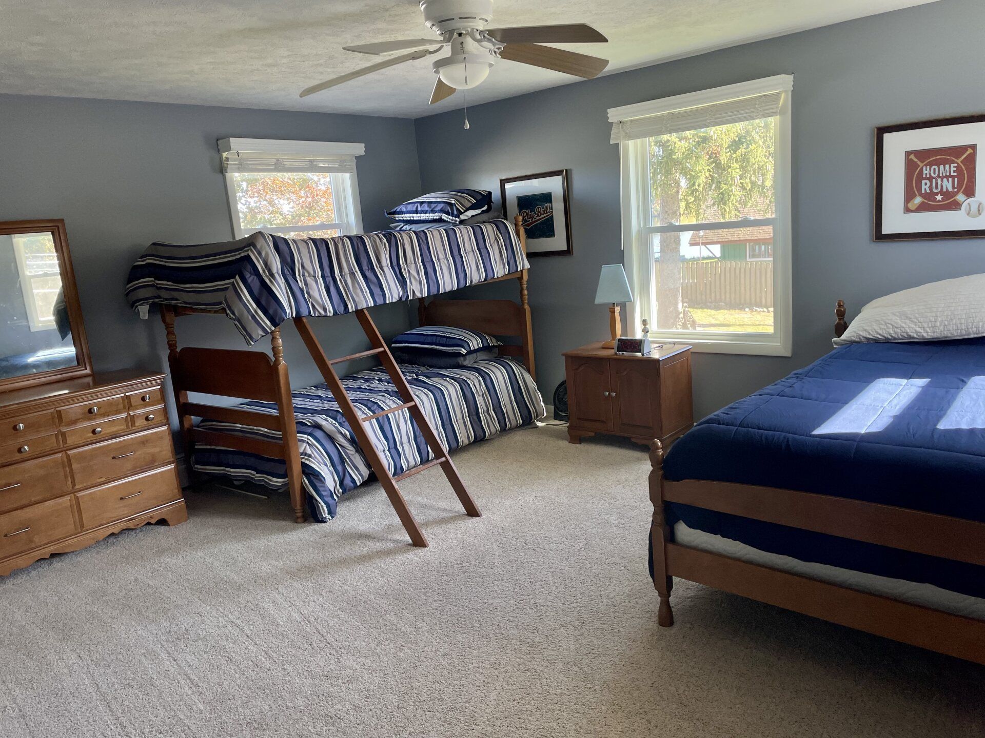 A bedroom with two beds, a dresser, a mirror, and a ceiling fan.