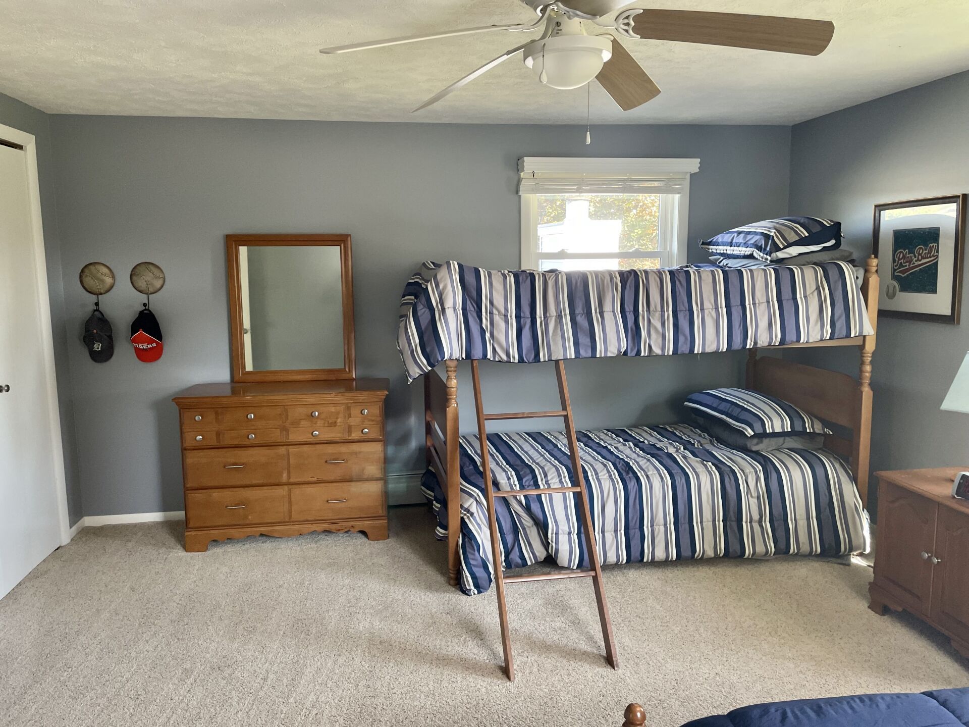 A bedroom with bunk beds, a dresser, a mirror, and a ceiling fan.