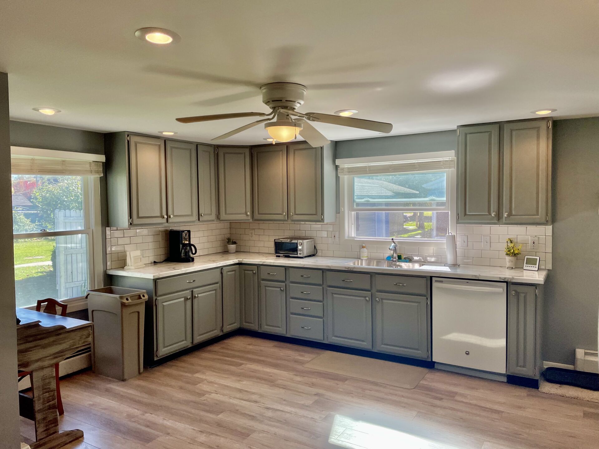A kitchen with gray cabinets and a ceiling fan.