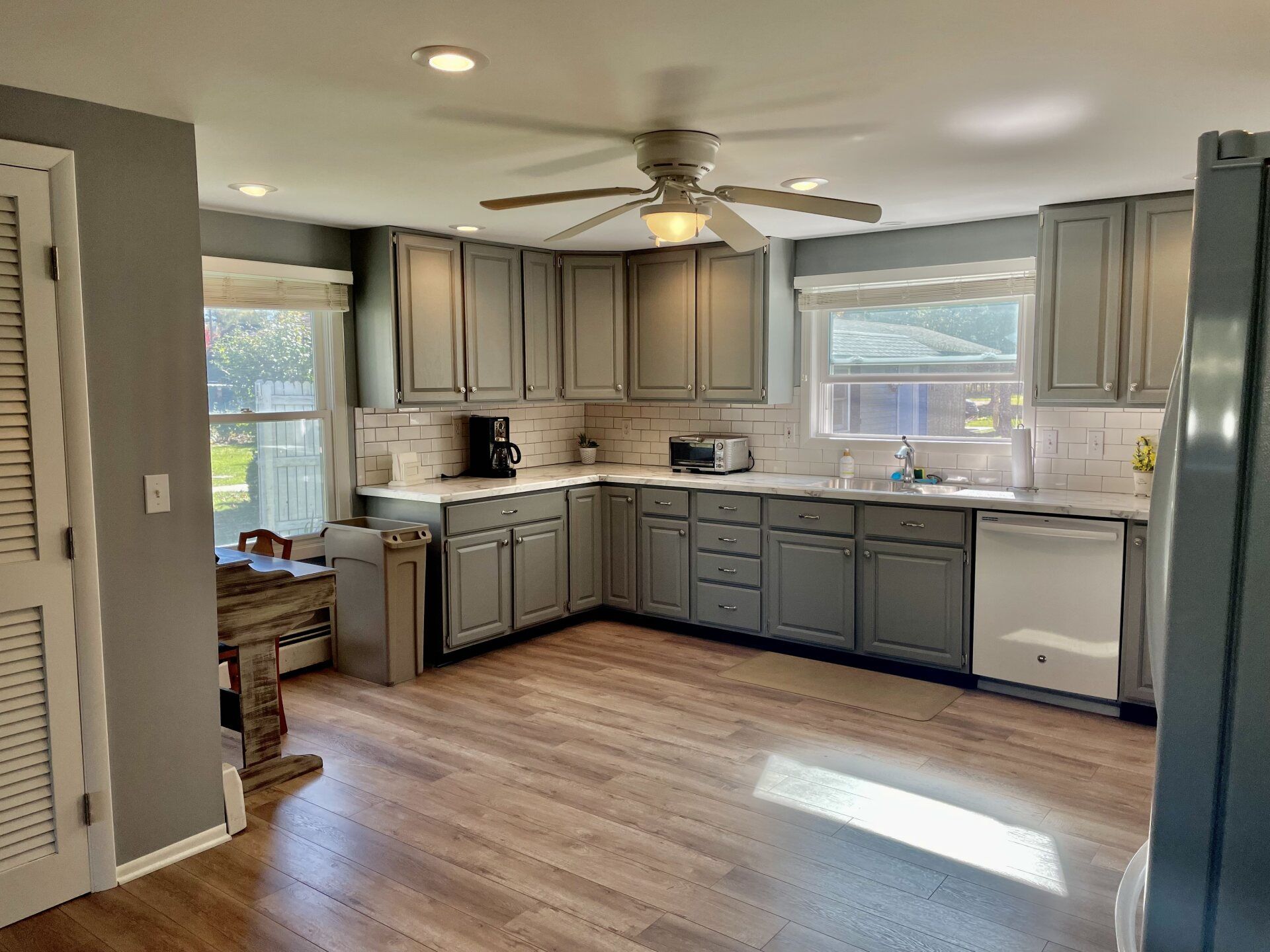 A kitchen with gray cabinets and a ceiling fan.