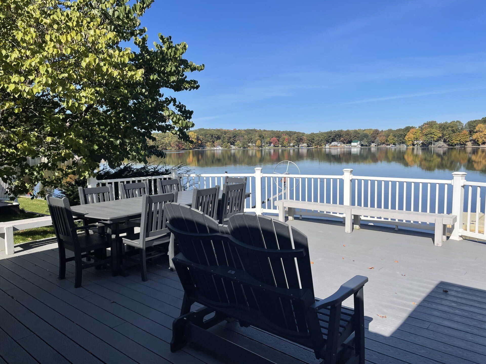 A deck with a table and chairs overlooking a lake.