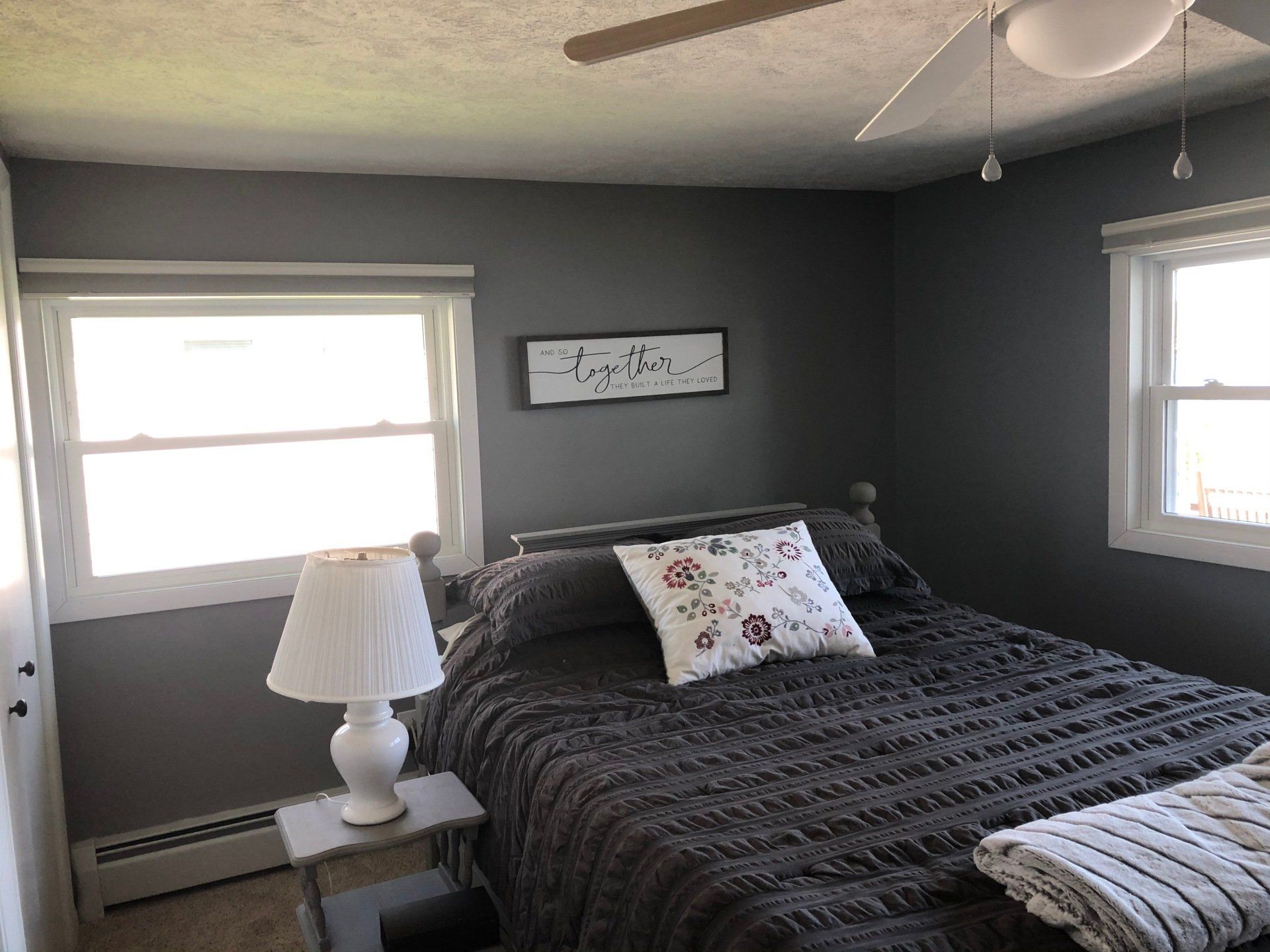 A bedroom with a bed , lamp , and ceiling fan.