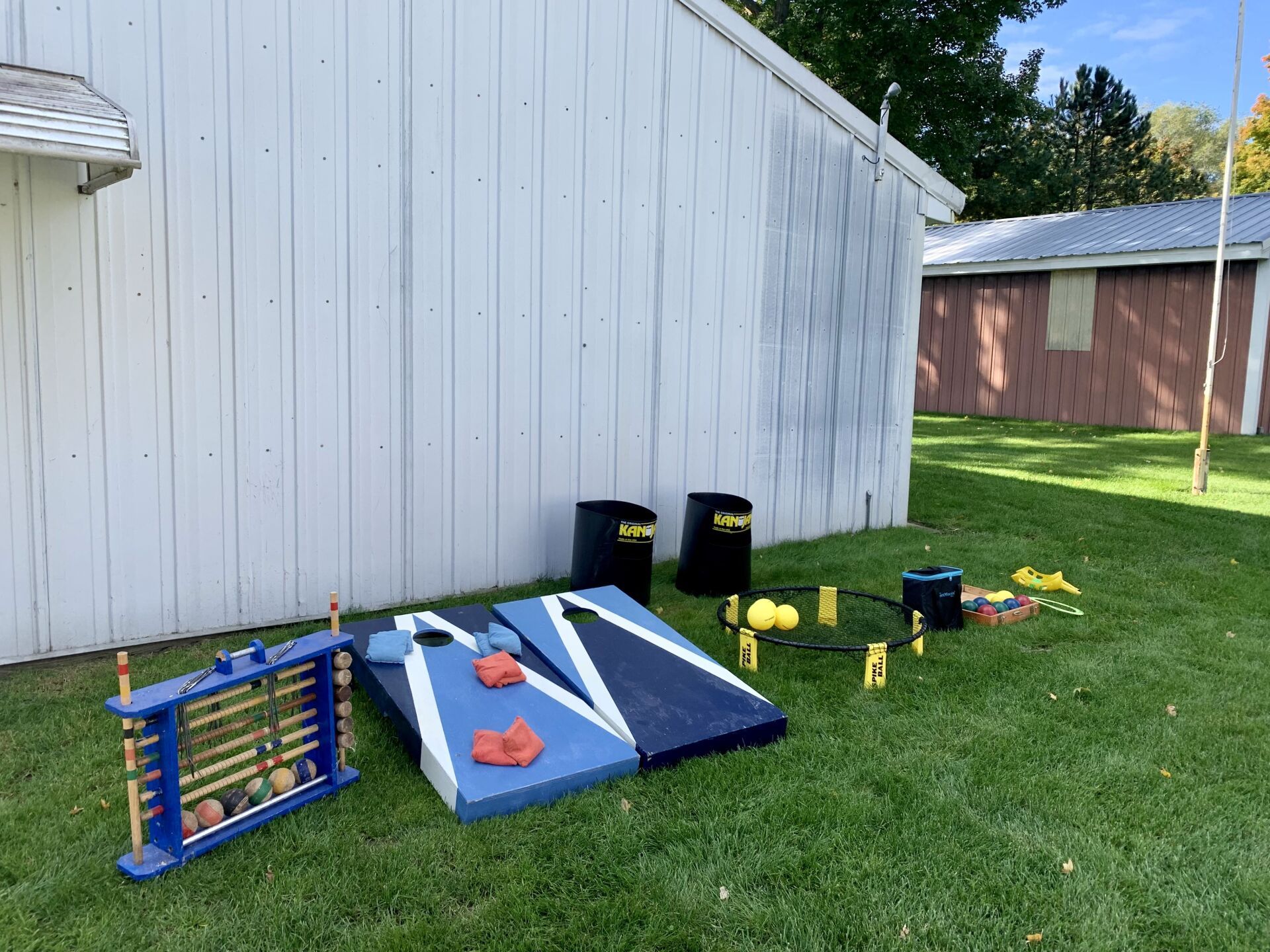 A bunch of games are sitting on the grass in front of a white building.