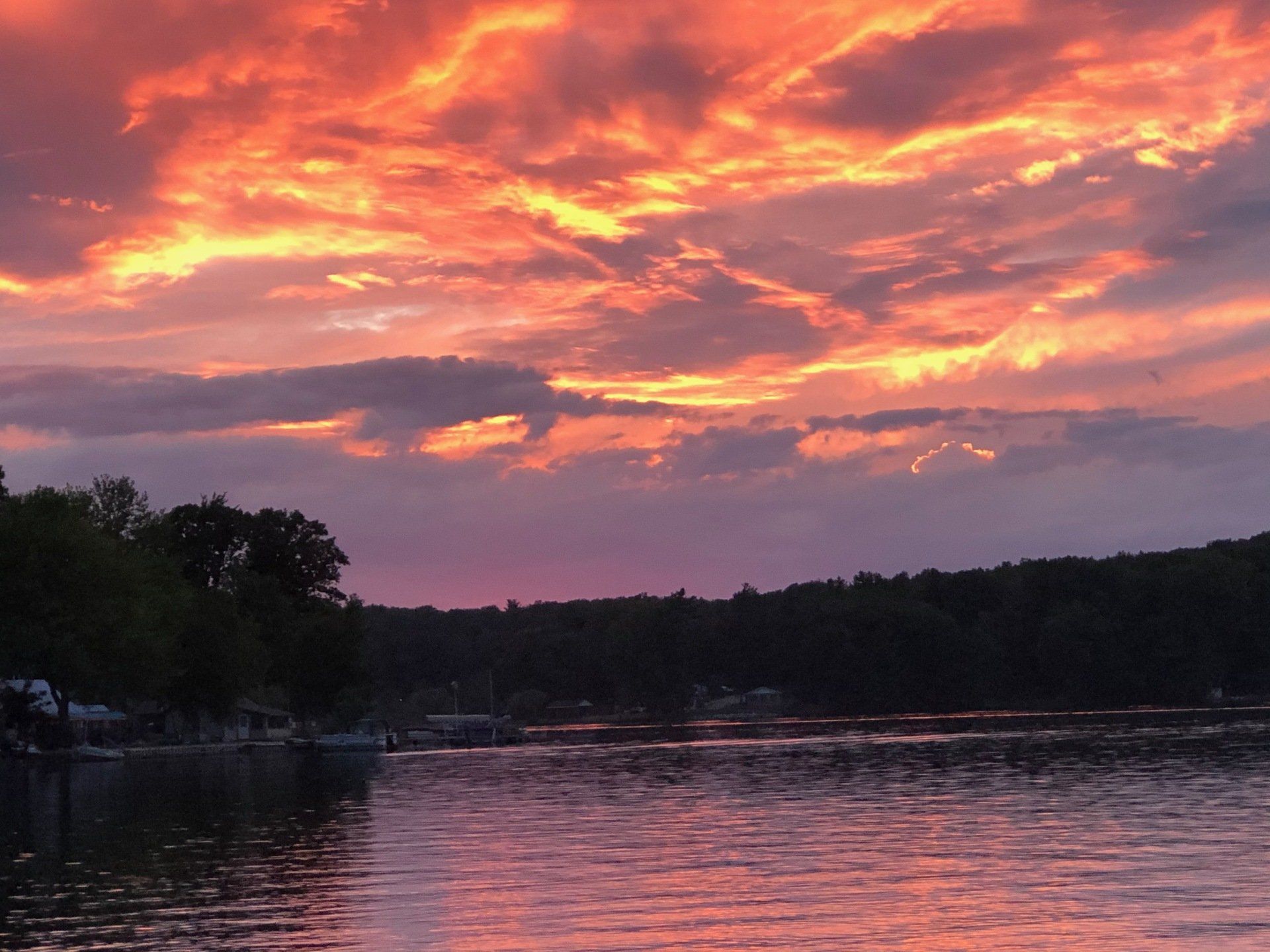 A sunset over a lake with trees in the background