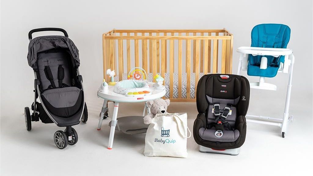 A stroller , high chair , crib , and activity table are sitting next to each other on a table.