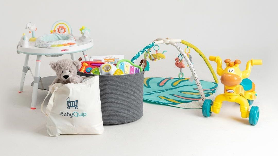 A teddy bear is sitting in a basket next to a high chair and a play mat.